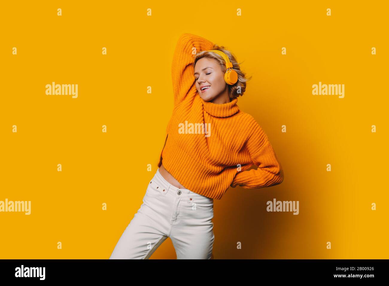 Une magnifique fille qui écoute de la musique et est complètement isolée de notre monde dans son casque jaune et de la musique de charme en arrière-plan Banque D'Images