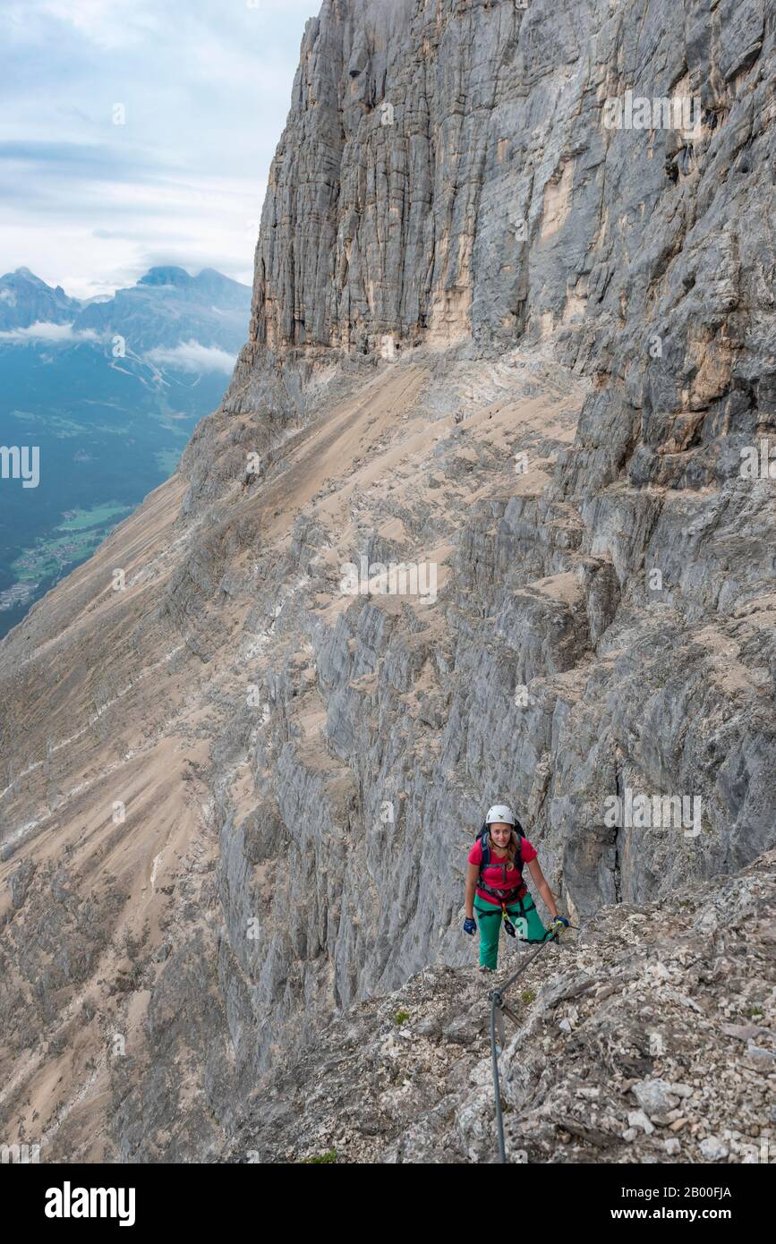 Jeune femme, randonneur attaché avec casque d'escalade sur un visage de roche, Via ferrata Francesco Berti, Sorapiss circuit, Dolomites, Belluno, Italie Banque D'Images