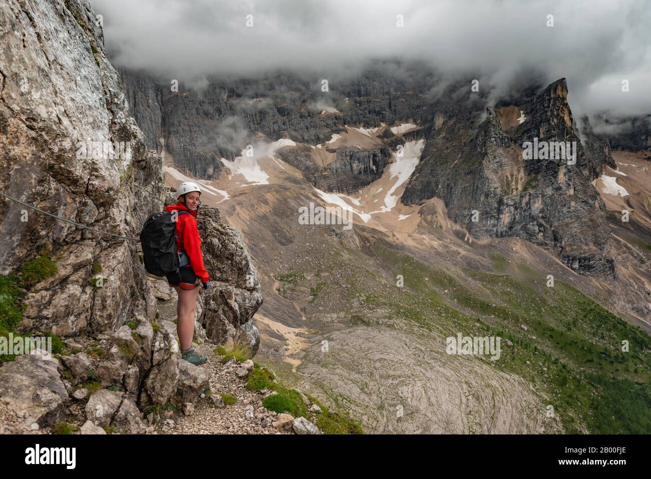 Jeune femme, randonneur grimpant sur la via ferrata Vandelli, circuit de Sorapiss, montagnes à faible nuage, Dolomites, Belluno, Italie Banque D'Images