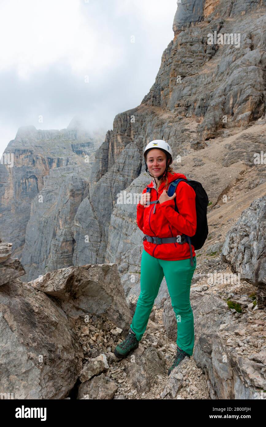 Jeune femme, randonneur avec casque d'escalade devant un rocher, Via ferrata Francesco Berti, Sorapiss circuit, Dolomites, Belluno, Italie Banque D'Images