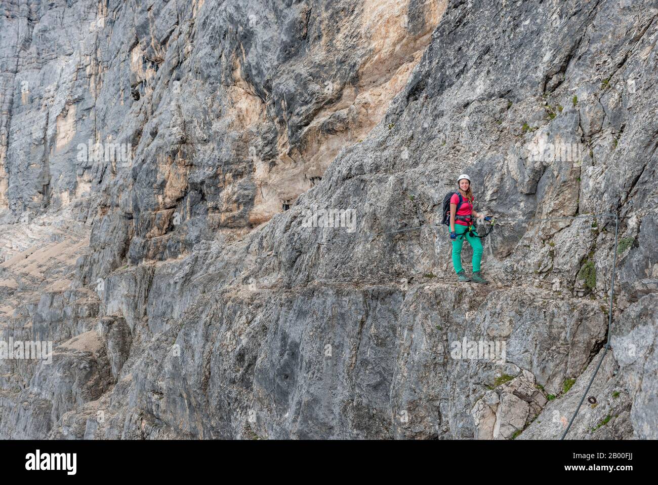 Jeune femme, Hiker arriva avec un casque d'escalade devant un rocher, Via ferrata Francesco Berti, Sorapiss circuit, Dolomites, Belluno Banque D'Images