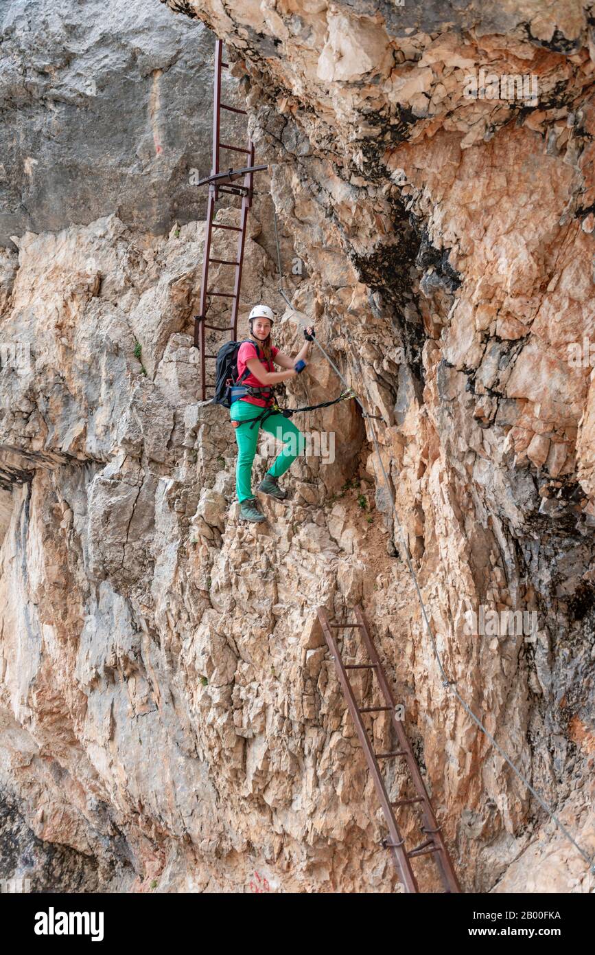 Jeune femme, randonneur descend l'échelle, tout en grimpant dans une via ferrata fixée sur un câble en acier, Via ferrata Francesco Berti, circuit de Sorapiss Banque D'Images