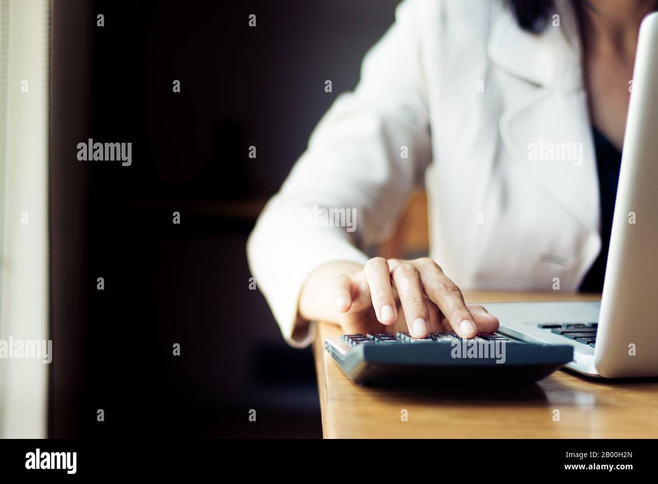 Femme d'affaires asiatique utilisant la calculatrice pour la comptabilité et l'analyse des investissements devant l'ordinateur portable au bureau. Banque , épargne , ac Banque D'Images