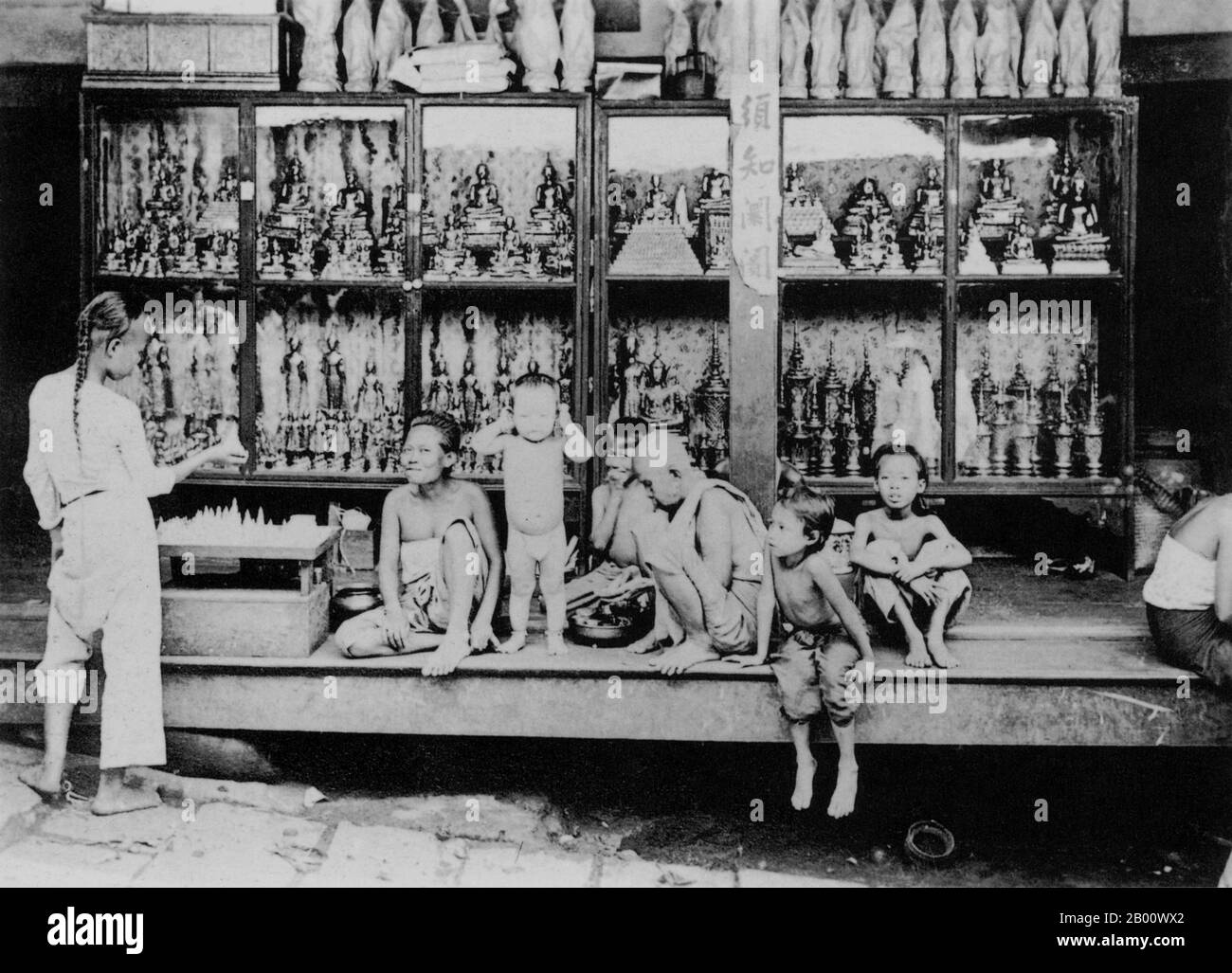 Thaïlande: Un magasin vendant des statuettes de Bouddha à Nong Khai dans le nord-est de Siam en 1920. Le bouddhisme en Thaïlande est en grande partie de l'école Theravada. Près de 95% de la population thaïlandaise est bouddhiste Theravada, bien que le bouddhisme dans ce pays ait été intégré aux croyances populaires ainsi que les religions chinoises de la grande population thaï-chinoise. Les temples bouddhistes de Thaïlande sont caractérisés par de grands stupas d'or, et l'architecture bouddhiste de la Thaïlande est semblable à celle d'autres pays d'Asie du Sud-est, en particulier le Cambodge et le Laos. Banque D'Images