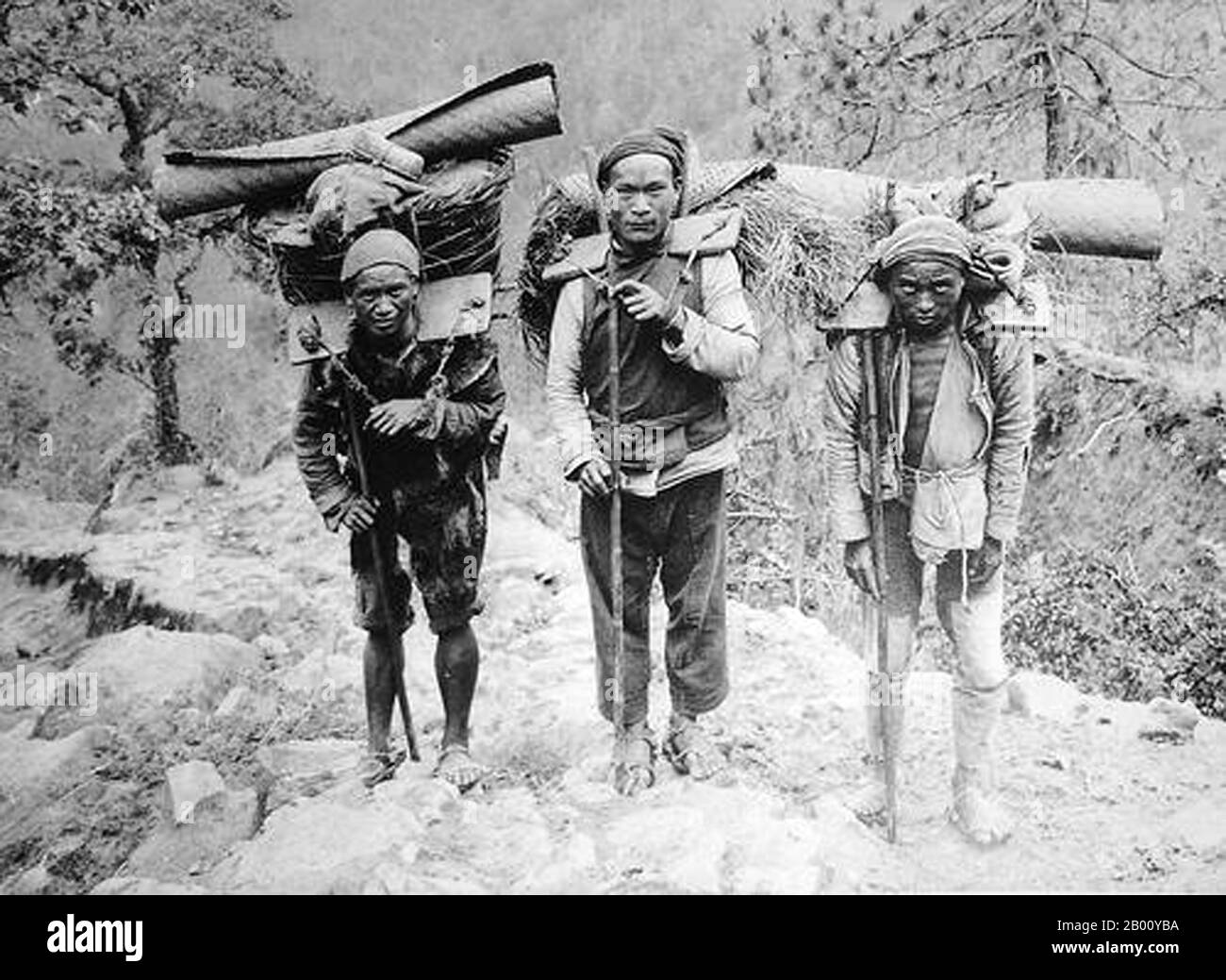 Chine : Bai Porters de nationalité près de Lijiang, province du Yunnan, 1923. Les Bai vivent principalement dans les provinces du Yunnan (région de Dali), et dans les provinces voisines de Guizhou (région de Bijie) et de Hunan (région de Sangzhi). Sur les 2 millions de Bai, 80 pour cent vivent dans des communautés concentrées dans la préfecture autonome de Dali Bai, dans la province du Yunnan. Banque D'Images