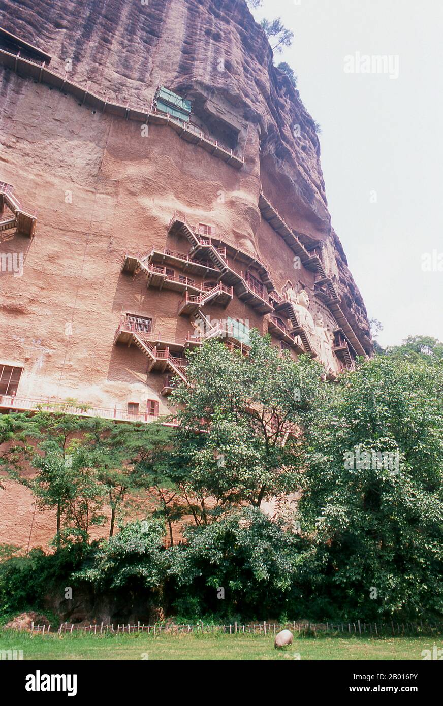 Chine : des escaliers sillonnent les grottes de Maiji Shan, Tianshui, province de Gansu.Maijishan Shiku (grottes de Maiji Shan) est l’un des quatre groupes de temples bouddhistes les plus importants de Chine (les autres étant Datong, Luoyang et les grottes de Mogao à Dunhuang).À partir des dynasties de Wei du Nord (386-535) et de Zhou du Nord (557-81), les bouddhistes tachent des grottes sur les côtés d'un affleurement rouge qui s'élève des collines couvertes de feuillage environnantes.Les figures du Bouddha, des bodhisattvas et des disciples ont été sculptées dans le rocher plus dur apporté d'ailleurs, et installées dans les grottes. Banque D'Images
