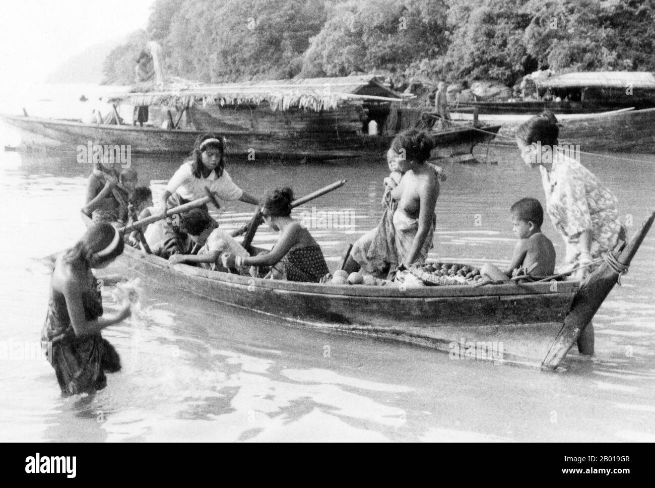 Thaïlande: Chao Thalae 'sea Gypsy' femmes et enfants avec bateaux, Phuket, ch. 1960. Les «sea Gitans» ou Moken de la mer d'Andaman, connus en thaï sous le nom de chao thalae ou de «peuple de la mer», sont divisés en trois groupes. Ils sont entre 4 000 et 5 000, ils ne vivent que sur la côte, soit dans des huttes au bord de la côte, soit dans des bateaux qui sillonnent les eaux côtières de l'archipel de Mergui en Birmanie aux îles Tarutao en Thaïlande du Sud. Le plus grand groupe de Gypsy de mer est le Urak Lawoi, qui se chiffre autour de 3 000. Ils vivent dans des cabanes simples sur des plages s'étendant au sud de Phuket aux îles Tarutao. Banque D'Images