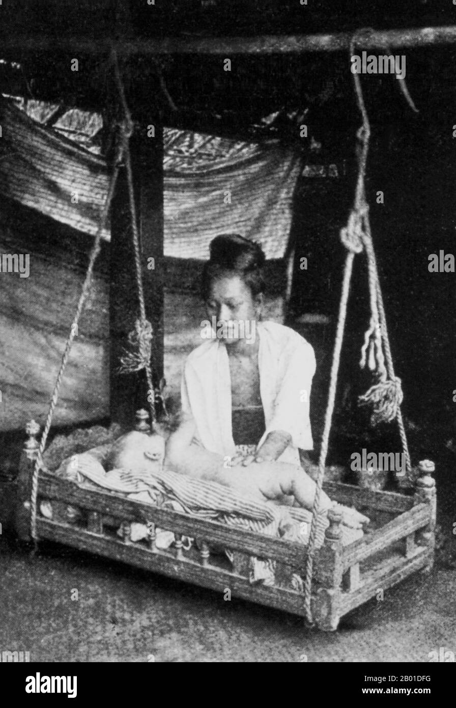 Birmanie: Une mère birmane s'occupe de son enfant qui se trouve dans un berceau en bois balançoire (birman: 'Sunngban'), vers 1892-1896. La conquête britannique de la Birmanie a commencé en 1824 en réponse à une tentative birmane d'envahir l'Inde. En 1886, et après deux autres guerres, la Grande-Bretagne avait incorporé tout le pays dans le Raj britannique. Pour stimuler le commerce et faciliter les changements, les Britanniques ont fait venir des Indiens et des Chinois, qui ont rapidement déplacé les Birmans dans les zones urbaines. À ce jour, Rangoon et Mandalay ont de grandes populations indiennes ethniques. Des chemins de fer et des écoles ont été construits, ainsi qu'un grand nombre de prisons. Banque D'Images