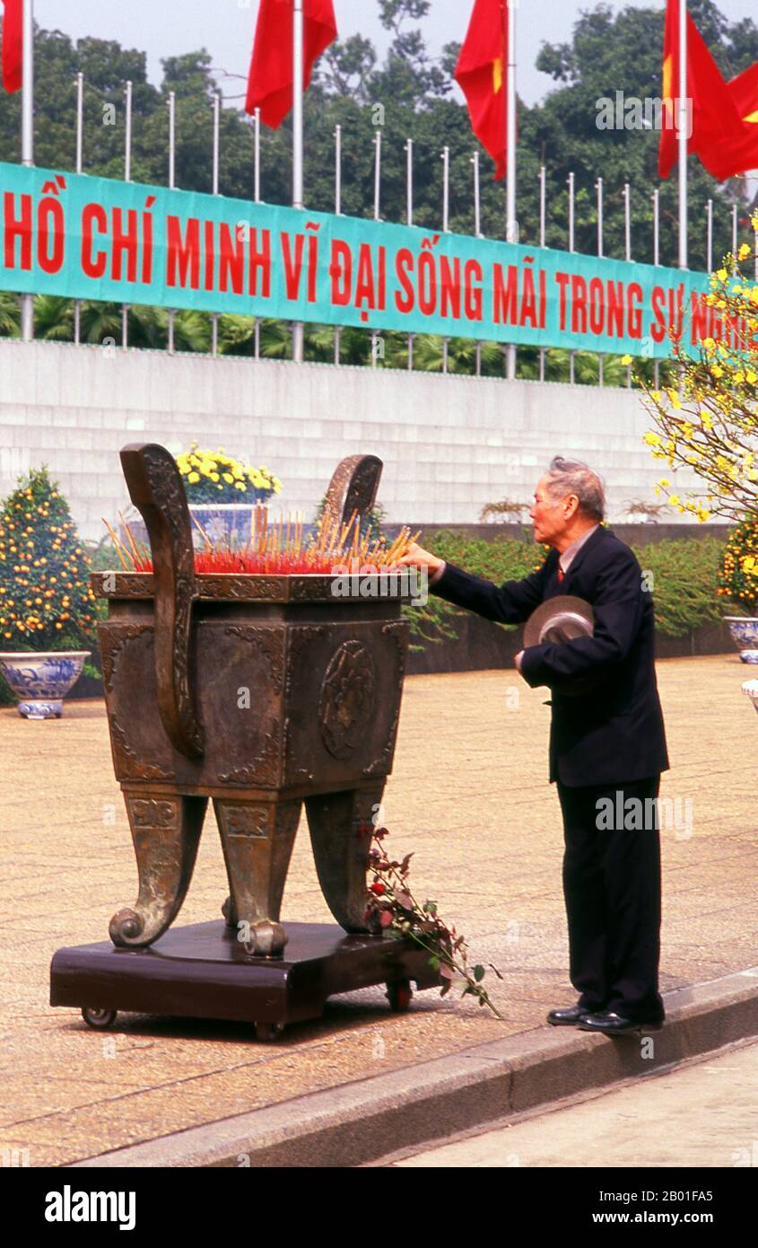 Vietnam : un homme place un bâton d'encens dans une urne géante en face du mausolée d'Ho Chi Minh, place Ba Dinh, Hanoï. La place BA Dinh a une importance particulière pour les Vietnamiens, car c’est ici que Ho Chi Minh a déclaré l’indépendance de la nation par rapport à la France devant une foule de plus de 100 000 personnes le 2 septembre 1945. Le mausolée d'Ho Chi Minh se trouve sur le côté ouest de la place Ba Dinh, une structure grise lourde, face en pierre extraite de Marble Mountain près de Danang. Ho Chi Minh a expressément demandé qu'il soit incinéré et que ses cendres soient dispersées dans tout le Vietnam, une demande qui a été refusée Banque D'Images