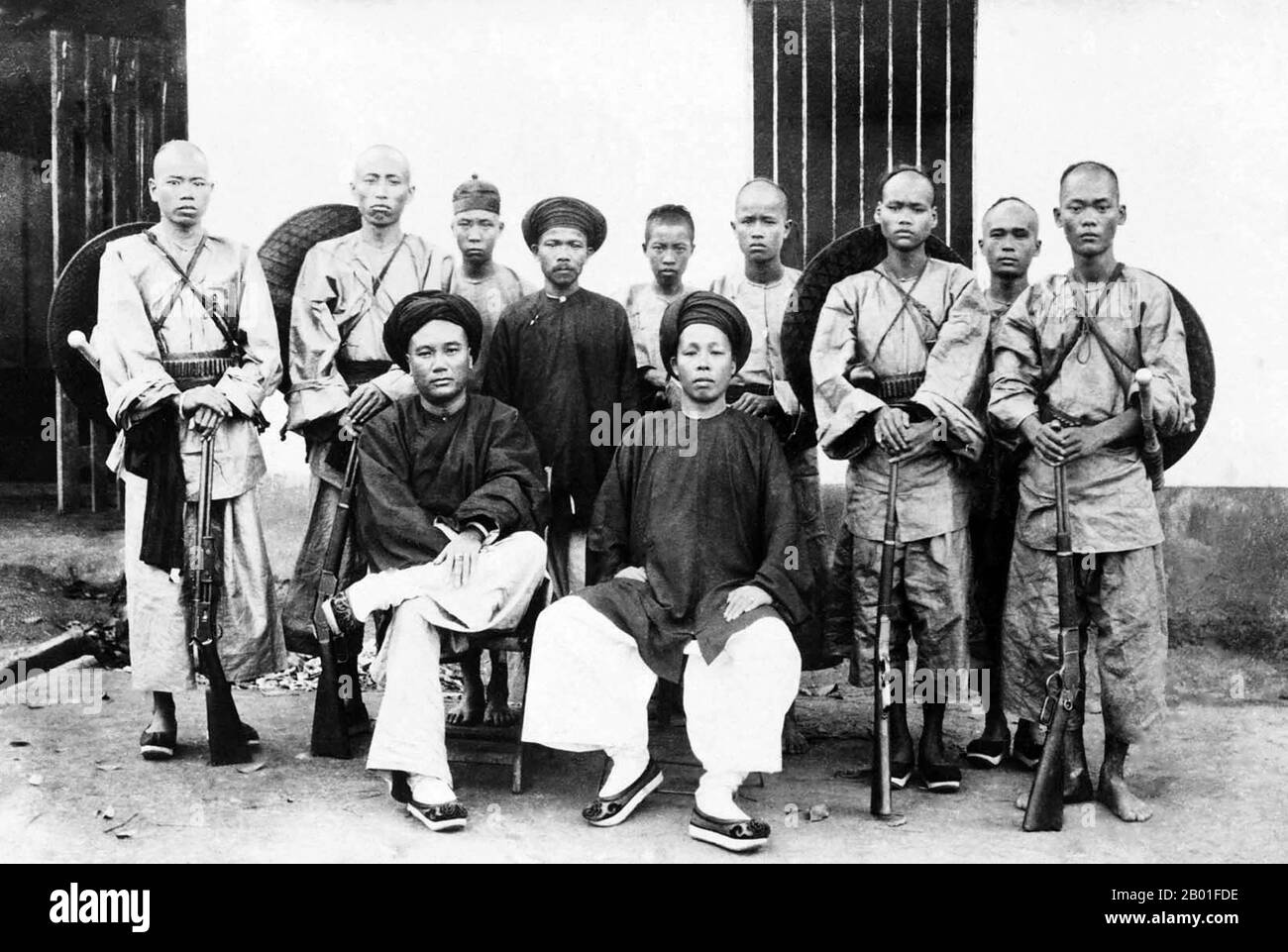 Vietnam : DEO Van Tri (Kham OUN), seigneur de la Fédération de Tai de Sipsongchuthai (1849-1908), assis avec Kham Doi et gardé par la milice, vers 1900. À la fin du siècle 19th, tout le territoire s'étendant de Dien bien Phu au sud jusqu'à la frontière chinoise au nord forme une région autonome appelée Sipsongchutai, ou «douze principes de Tai». Il a été dirigé par un prince de Tai blanc héréditaire de sa capitale à Lai Chau et a rendu hommage, à un moment ou à un autre, au Siam, au Vietnam ou à la Chine, et parfois aux trois. Banque D'Images