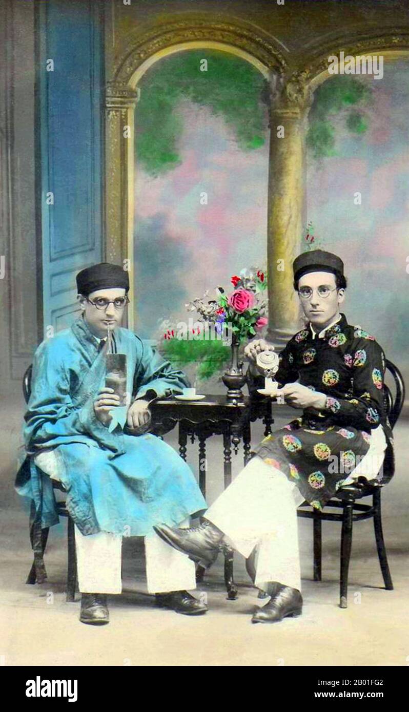 Vietnam: Deux hommes assis, probablement Parsis ou Juifs indiens, portant des hommes ao dai ou vietnamienne 'longue robe', Hanoi, 1910. L'ao dai (vietnamien: Áo dài) est un costume national vietnamien, aujourd'hui le plus souvent pour les femmes. Dans sa forme actuelle, il s'agit d'une tunique en soie ajustée sur des pantaluons. Le mot est prononcé [ǎːwzâːj]. Áo est dérivé d'un mot chinois moyen signifiant 'manteau matelassé' (襖). Dài signifie « long ». Le mot 'ao dai' a été appliqué à l'origine à la tenue portée à la cour des seigneurs de Nguyễn à Huế au 18th siècle. Cette tenue a évolué en l'áo ngũ thân. Banque D'Images