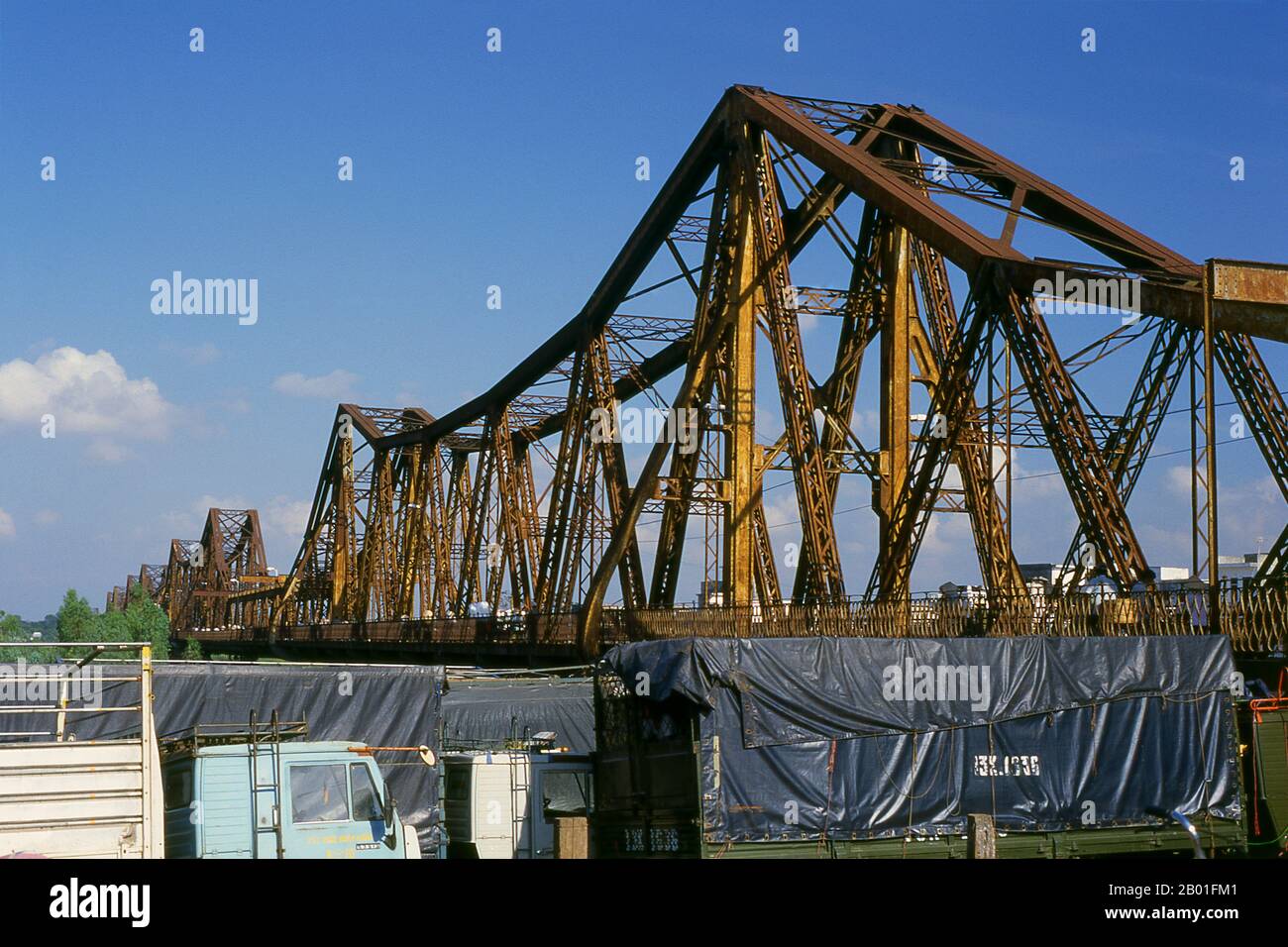 Vietnam : le pont de long Bien, Hanoï. Le pont de long-bien fut érigé par les colonialistes français entre 1899 et 1902 et nommé le pont Paul Doumer en l'honneur du gouverneur de l'Indochine française de l'époque (1897-1902). Il a été conçu et construit par Dayde et Pille de Paris (les plaques originales sont toujours en place) et est de 1 682 mètres (5 518 pi) de long, comprenant 18 travées, avec une portée centrale supplémentaire allongée de 106 mètres (347 pi). Il transporte la seule ligne ferroviaire entre Hanoï et Haiphong, ainsi que deux liaisons ferroviaires vitales avec la Chine. Banque D'Images