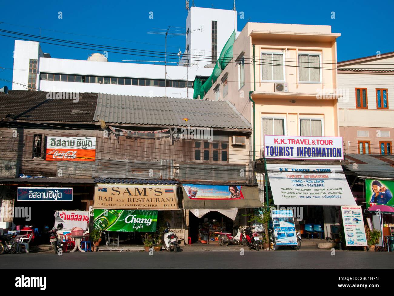 Thaïlande : agents de voyage et restaurants dans les anciens magasins en bois près de la gare, Trang, province de Trang. Trang est un centre commercial depuis au moins le 1e siècle de notre ère. Elle a grandi au pouvoir et à la prospérité entre les 7e et 13e siècles au cours de la période Srivijaya et reste aujourd'hui une importante ville commerciale. Le caoutchouc, l'huile de palme et la pêche sont les piliers de l'économie de la province. Le tourisme a un impact croissant alors que la côte et les îles Anadaman de Trang sont de plus en plus développées et popularisées. La ville a un fort caractère chinois outre-mer. Banque D'Images