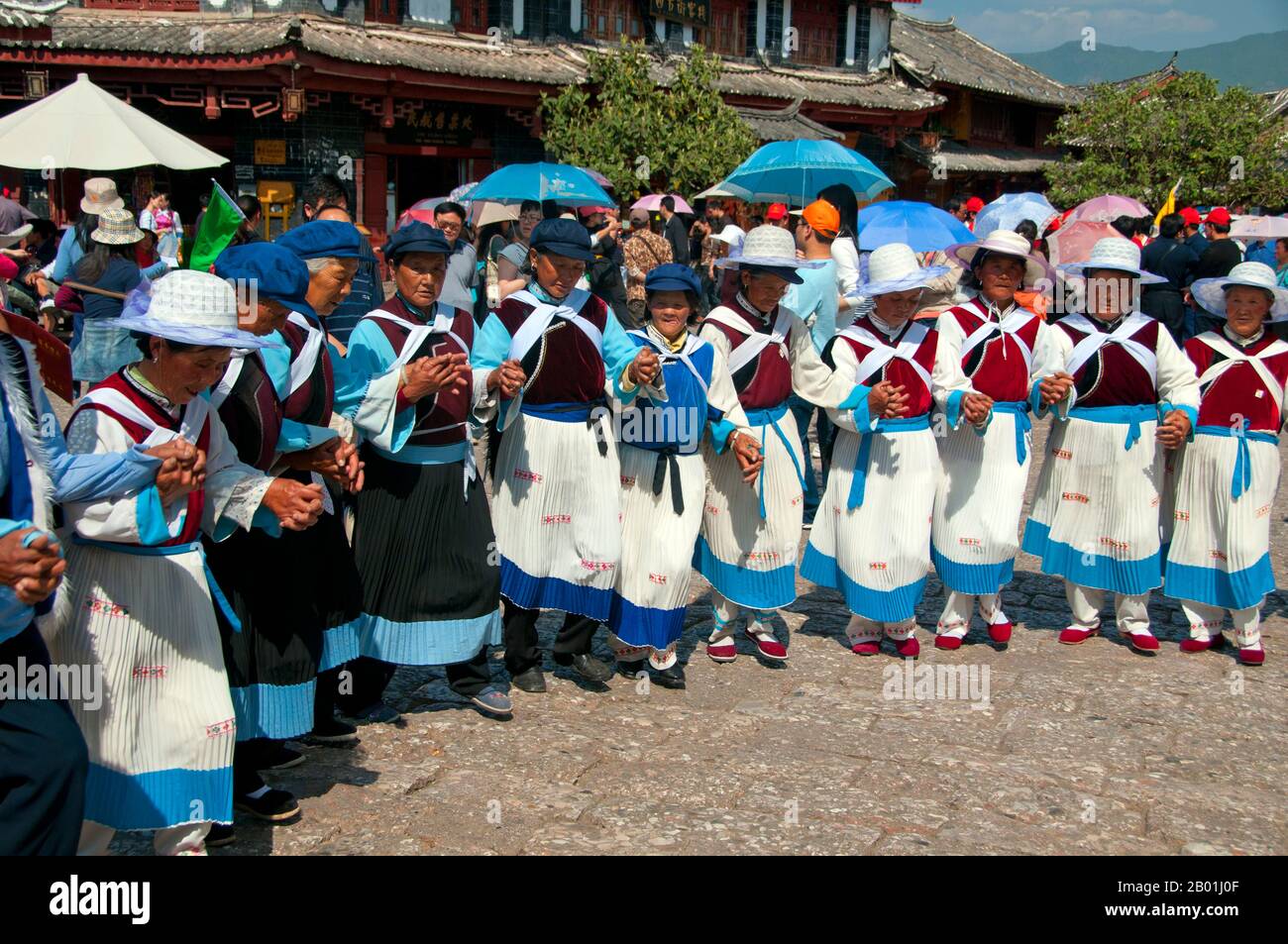 Chine : les femmes Naxi dansent sur la place du Vieux marché (Sifang Jie), vieille ville de Lijiang, province du Yunnan. Les Naxi ou Nakhi sont un groupe ethnique habitant les contreforts de l'Himalaya dans la partie nord-ouest de la province du Yunnan, ainsi que la partie sud-ouest de la province du Sichuan en Chine. On pense que les Naxi sont originaires du Tibet et, jusqu'à récemment, entretenaient des liens commerciaux terrestres avec Lhassa et l'Inde. Les Naxi forment l'un des 56 groupes ethniques officiellement reconnus par la République populaire de Chine. Les Naxi sont traditionnellement adeptes de la religion Dongba. Banque D'Images