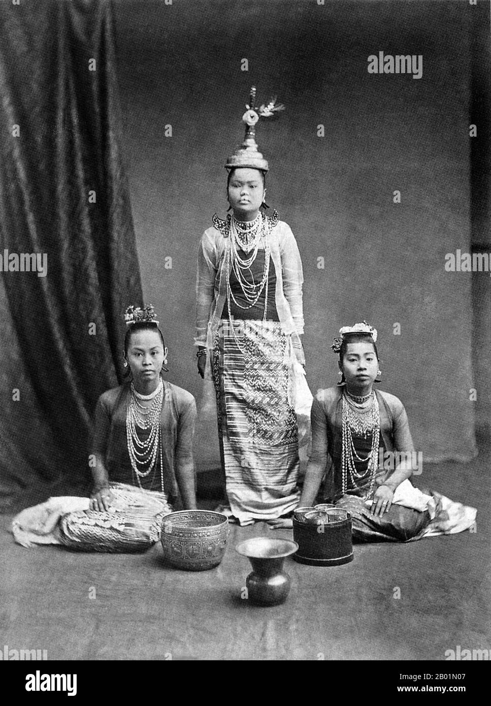 Birmanie/Myanmar : Portrait en studio d'un groupe professionnel de danseurs Bamar, vers les années 1870 La conquête britannique de la Birmanie a commencé en 1824 en réponse à une tentative birmane d'envahir l'Inde. En 1886, et après deux autres guerres, la Grande-Bretagne avait incorporé tout le pays dans le Raj britannique. Pour stimuler le commerce et faciliter les changements, les Britanniques ont fait venir des Indiens et des Chinois, qui ont rapidement déplacé les Birmans dans les zones urbaines. À ce jour, Rangoon et Mandalay ont de grandes populations indiennes ethniques. Des chemins de fer et des écoles ont été construits, ainsi qu'un grand nombre de prisons, dont la tristement célèbre prison d'Insein. Banque D'Images