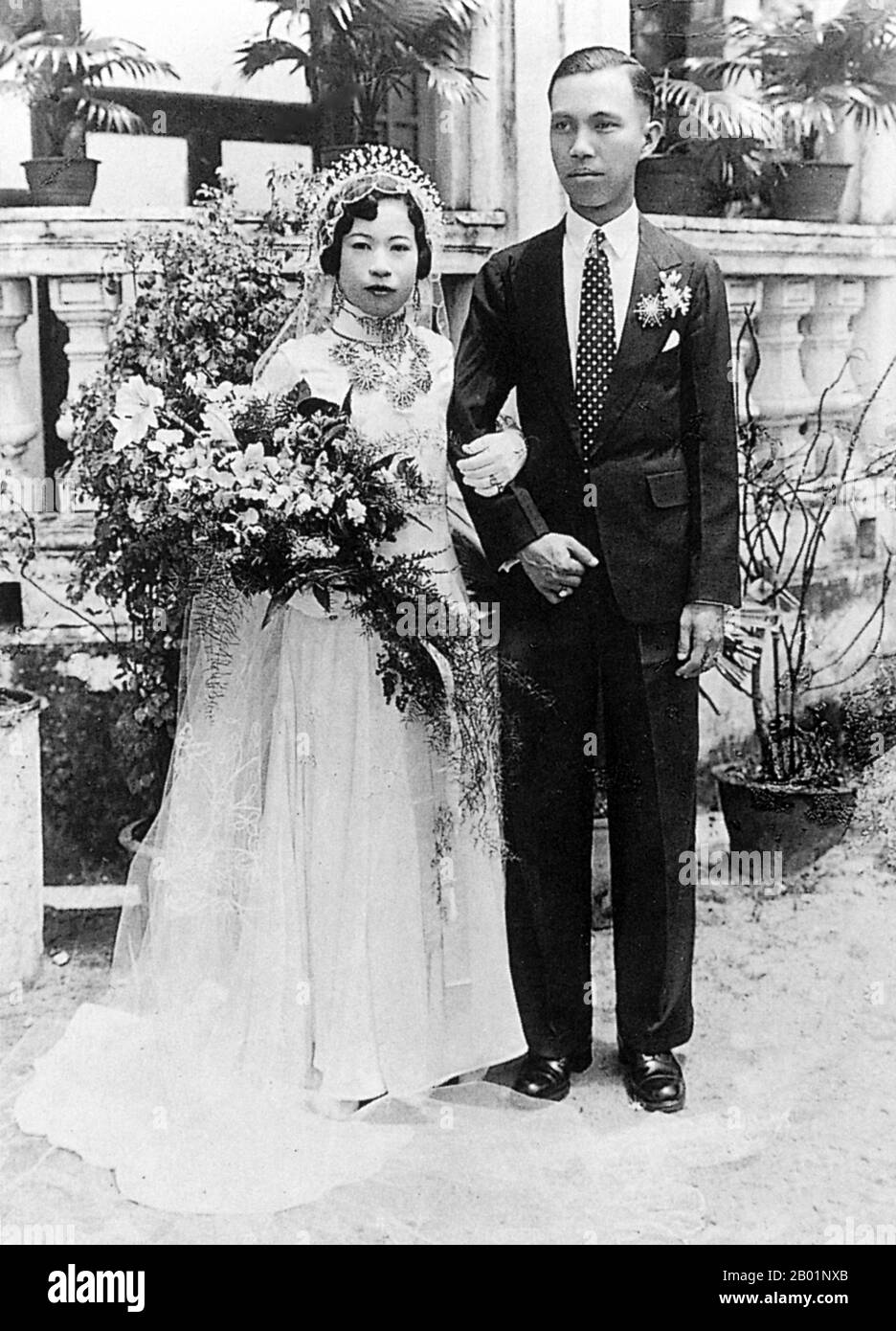 Malaisie/Singapour : mariée et marié Peranakan, milieu du 20e siècle. Peranakan Chinese et Baba-Nyonya sont des termes utilisés pour désigner les descendants des immigrants chinois de la fin des 15e et 16e siècles dans l'archipel malais-indonésien de Nusantara pendant l'ère coloniale. Les membres de cette communauté en Malaisie s'identifient comme 'Nyonya-Baba' ou 'Baba-Nyonya'. Nyonya est le terme pour les femelles et Baba pour les mâles. Elle s ' applique en particulier aux populations chinoises de souche des établissements britanniques du détroit de Malaisie et de l ' île de Java contrôlée par les Néerlandais et d ' autres localités. Banque D'Images