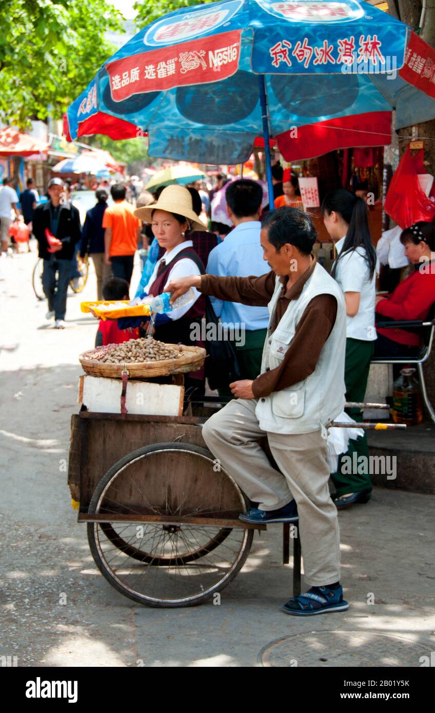 Chine : vendeur d'arachides près du marché aux oiseaux et aux fleurs dans le vieux quartier musulman sur la route de Jingxing au large de la route de Zheng Yi, Kunming, province du Yunnan. Construit sur les rives du lac Dian et entouré de montagnes calcaires, Kunming était une importante route commerciale ancienne entre le Tibet, la Chine et l'Asie du Sud-est. La ville, alors appelée Yunnanfu, a souffert des mains du chef rebelle du Wenxiu, le sultan de Dali, qui a attaqué et assiégé la ville à plusieurs reprises entre 1858 et 1868, rasant la plupart des temples bouddhistes de la ville. Banque D'Images