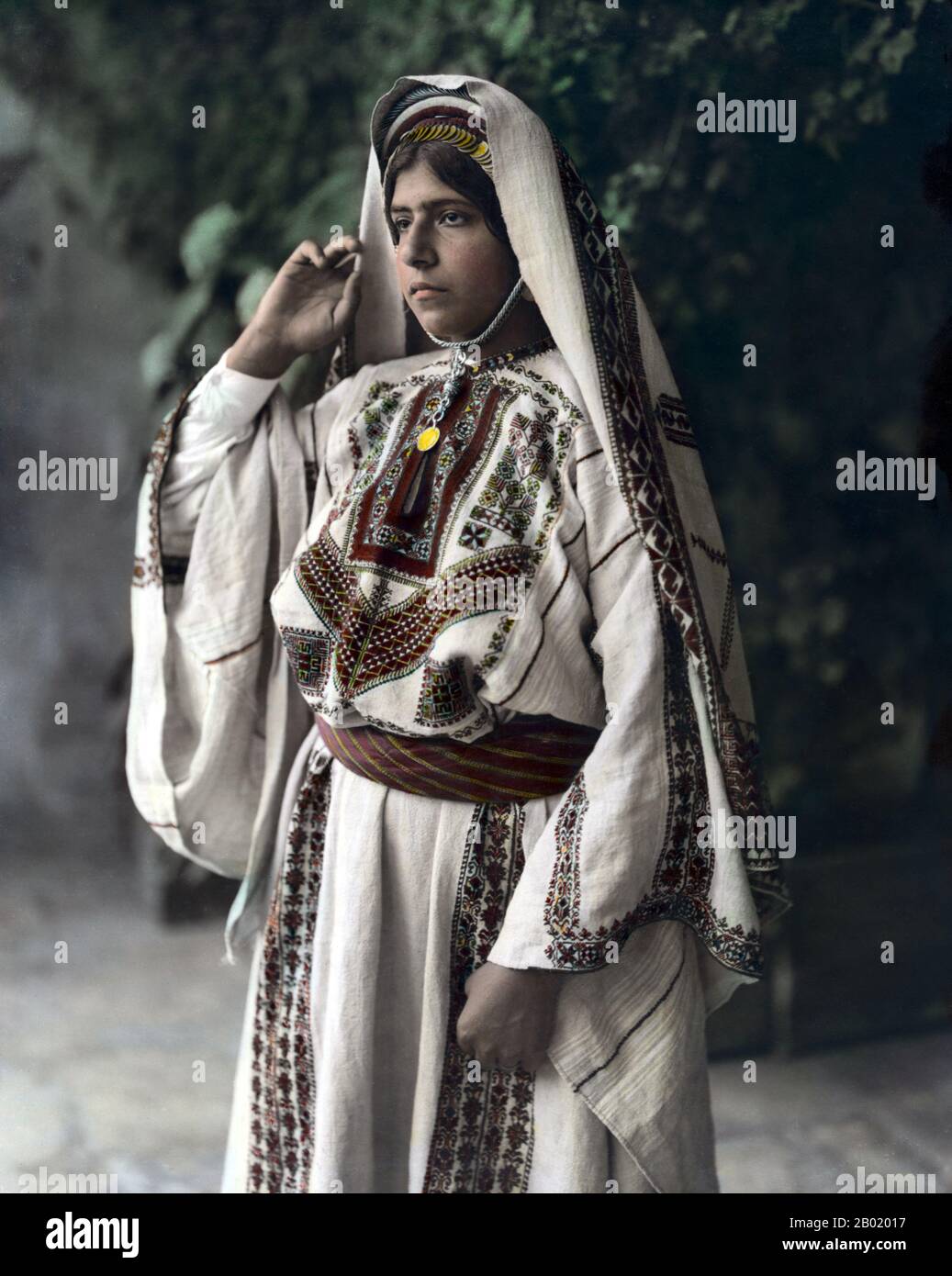 Palestine : Fahra Izhak Eadeh portant une robe brodée le jour de son mariage, Ramallah, c. 1898-1914. Palestine est un nom donné à la région géographique entre la mer Méditerranée et le Jourdain. La région est également connue comme la Terre d'Israël (Eretz-Yisra'el), la Terre Sainte et le Levant Sud. En 1832, la Palestine a été conquise par l'Égypte de Muhammad Ali, mais en 1840, la Grande-Bretagne est intervenue et a rendu le contrôle du Levant aux Ottomans en échange de nouvelles capitulations. La fin du XIXe siècle voit le début de l'immigration sioniste et la renaissance de la langue hébraïque. Banque D'Images