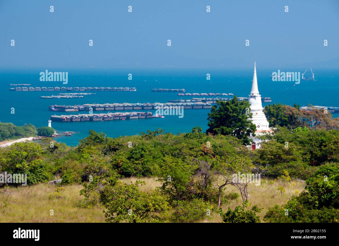 Thaïlande : stupa blanc à Wat Atsadang Nimit avec de grandes barges à l'ancre en arrière-plan, Ko Sichang, province de Chonburi. Le Wat Atsadang Nimit a été construit par le roi Chulalongkorn (Rama V) à la fin du XIXe siècle. Le roi l'utilisa pour la méditation. Ko si Chang a été occupé par les Français en 1893 et a été la retraite d'été de plusieurs rois siamois, y compris le roi Chulalongkorn (Rama V) dont le merveilleux palais en teck a été déplacé en 1901 de Ko si Chang à son emplacement actuel dans Dusit Park à Bangkok. L'île abrite également une espèce rare d'écureuil blanc. Banque D'Images