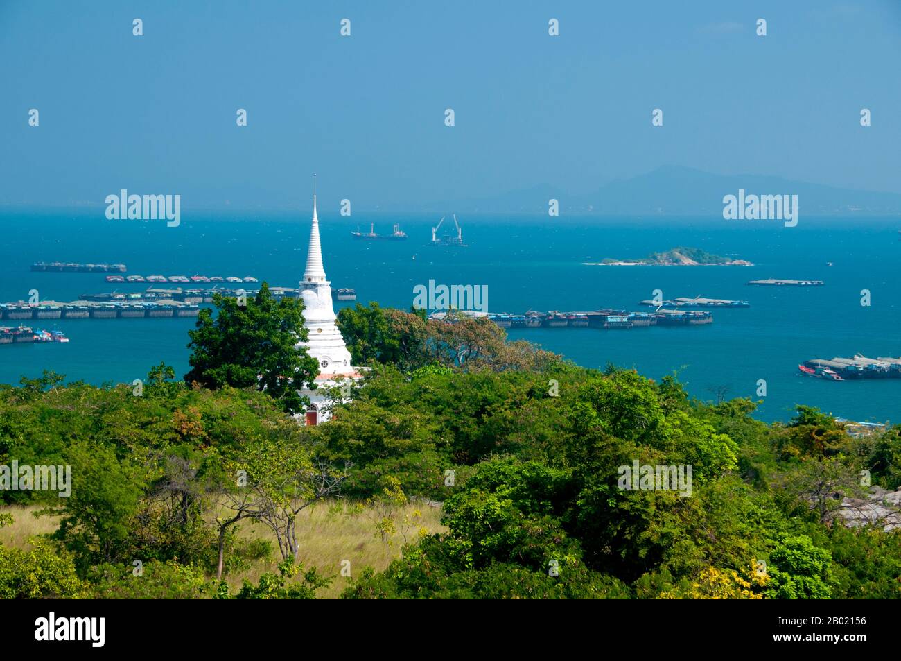 Thaïlande : stupa blanc à Wat Atsadang Nimit avec de grandes barges à l'ancre en arrière-plan, Ko Sichang, province de Chonburi. Le Wat Atsadang Nimit a été construit par le roi Chulalongkorn (Rama V) à la fin du XIXe siècle. Le roi l'utilisa pour la méditation. Ko si Chang a été occupé par les Français en 1893 et a été la retraite d'été de plusieurs rois siamois, y compris le roi Chulalongkorn (Rama V) dont le merveilleux palais en teck a été déplacé en 1901 de Ko si Chang à son emplacement actuel dans Dusit Park à Bangkok. L'île abrite également une espèce rare d'écureuil blanc. Banque D'Images