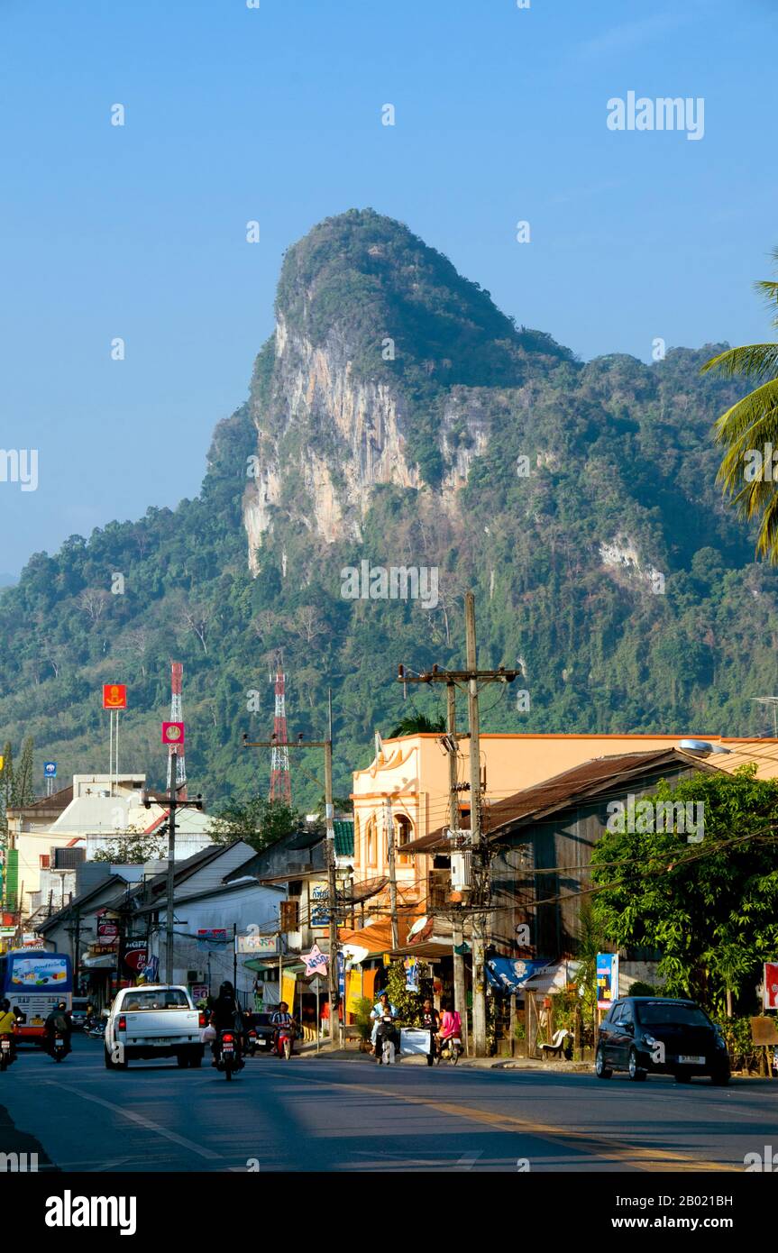 Thaïlande : des pics calcaires surplombent la rue principale de Phangnga Town. Phang Nga Town, la capitale de la province de Phang Nga, est une ville plutôt délabrée dans un endroit spectaculaire qui semble destiné à être toujours éclipsé par l'essor, voisin de Phuket. Il y a beaucoup à faire et à voir dans les environs, en particulier dans la belle baie de Phang Nga, mais très peu de visiteurs choisiront de rester en ville étant donné l'alléchant - et franchement beaucoup plus confortable - hébergement disponible dans les stations balnéaires voisines de l'île de Phuket. Banque D'Images