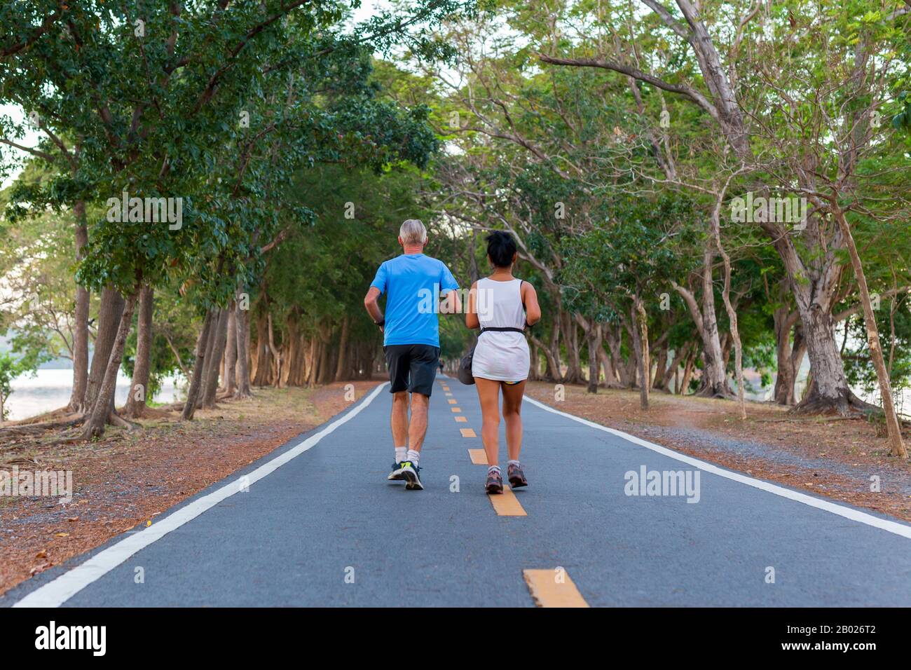 Vue arrière des couples seniors en jogging dans le parc public. Banque D'Images