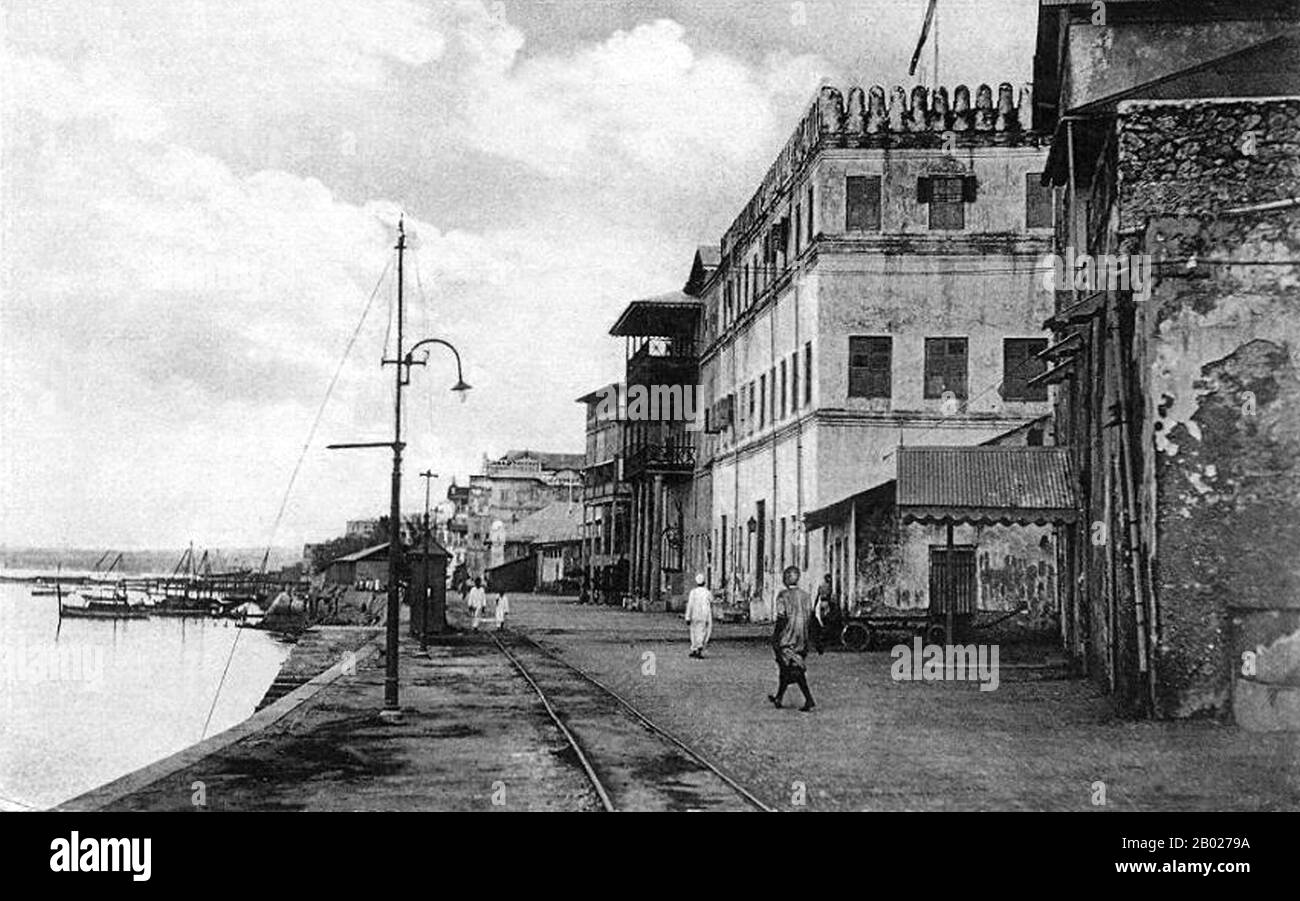 Tanzanie/Zanzibar : le front de mer et la ligne de chemin de fer à Mizigani Road, Stone Town, vers 1912. Zanzibar est une partie semi-autonome de la Tanzanie en Afrique de l'est. Il est composé de l'archipel de Zanzibar dans l'océan Indien, à 25-50 km (16-31 mi) au large des côtes du continent, et se compose de nombreuses petites îles et deux grandes : Unguja (l'île principale, appelée officieusement Zanzibar), et Pemba. La capitale de Zanzibar, située sur l'île d'Unguja, est la ville de Zanzibar. Son centre historique, connu sous le nom de Stone Town, est un site du patrimoine mondial. Banque D'Images