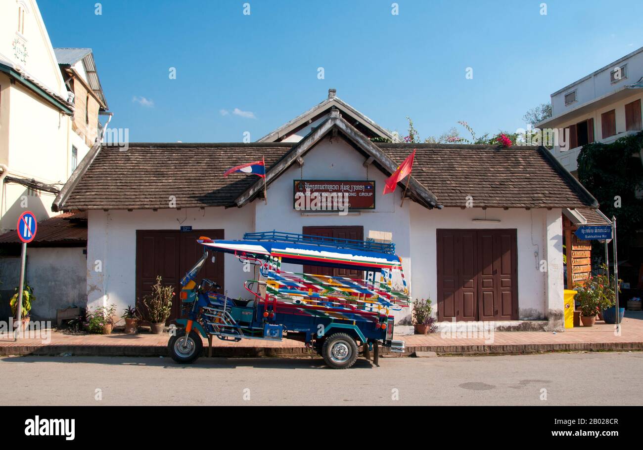 Laos : un jamboh (jumbo) garé devant le bureau de police sur Sisavangvong Road, Luang Prabang. Le « jumbo » est un taxi à trois roues et est le moyen de transport courant dans les grandes villes du Laos. Ce sont des motos modifiées avec deux bancs couverts à l'arrière qui assistent environ six personnes assez confortablement. Luang Prabang était autrefois la capitale d'un Royaume du même nom. Jusqu'à la prise de pouvoir communiste en 1975, elle était la capitale royale et le siège du gouvernement du Royaume du Laos. La ville est aujourd'hui classée au patrimoine mondial de l'UNESCO. Banque D'Images