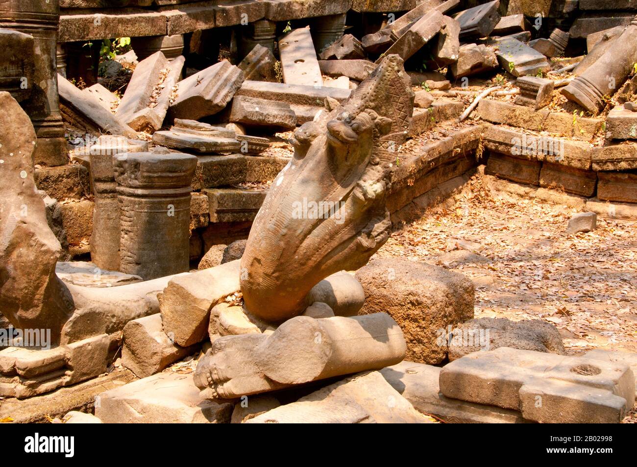 Cambodge : une balustrade Naga tombée à Beng Mealea (temple khmer du XIIe siècle), à 40 km à l'est du groupe principal de temples d'Angkor. Beng Mealea a été construit comme un temple hindou, mais il y a quelques sculptures représentant des motifs bouddhistes. Son matériau primaire est le grès et il est en grande partie non restauré, avec des arbres et des broussailles épaisses prospérant au milieu de ses tours et cours et beaucoup de ses pierres se trouvant dans de grands tas. Pendant des années, il était difficile d'atteindre, mais une route récemment construite pour le complexe du temple de Koh Ker passe Beng Mealea et plus de visiteurs viennent sur le site, car il est à 77 km de Siem Reap par la route. Banque D'Images