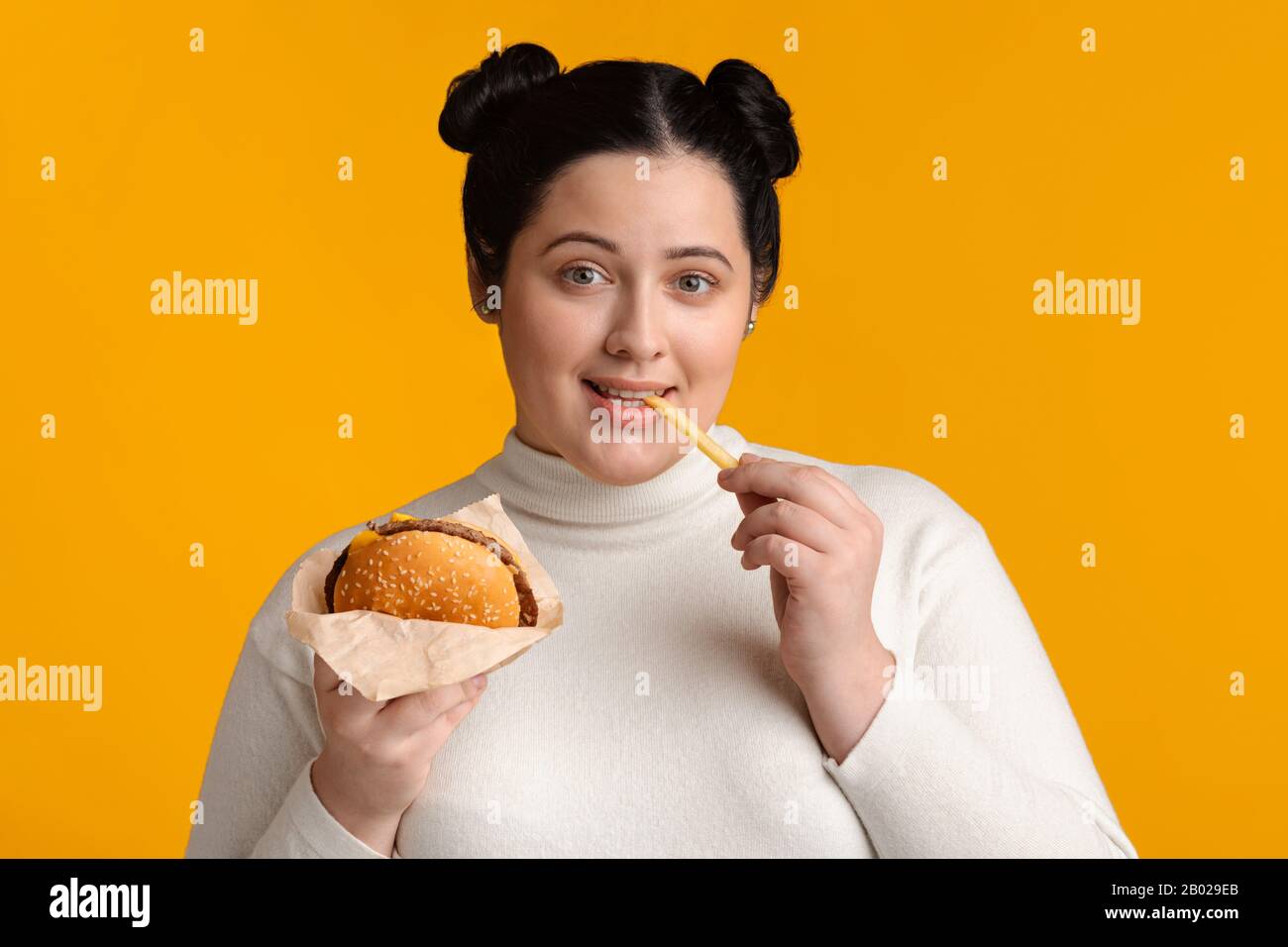 Jeune Femme En Surpoids En Profitant De La Restauration Rapide, Manger Du Hamburger Et Des Frites Banque D'Images