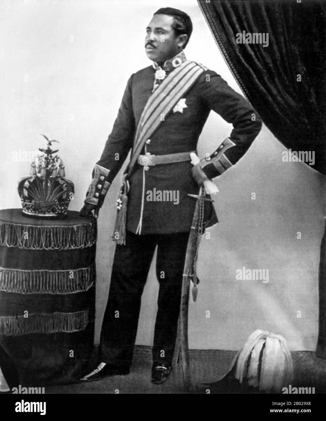 Madagascar : Roi Radama II (23 septembre 1829 - 12 mai 1863), posant avec la couronne royale. Photo de William Ellis, 1861. Radama II est le fils de la reine Ranavalona I et règne de 1861 à 1863 sur le Royaume de Madagascar. Le règne de Radama, bien que bref, fut une période charnière dans l'histoire du Royaume. Sous la ruIe de sa mère, Madagascar avait réussi à préserver son indépendance culturelle et politique vis-à-vis des desseins français et britanniques. Rejetant la politique d'isolationnisme et de persécution chrétienne de la reine, Radama II autorise la liberté religieuse et rouvre Madagascar à l'influence européenne. Banque D'Images