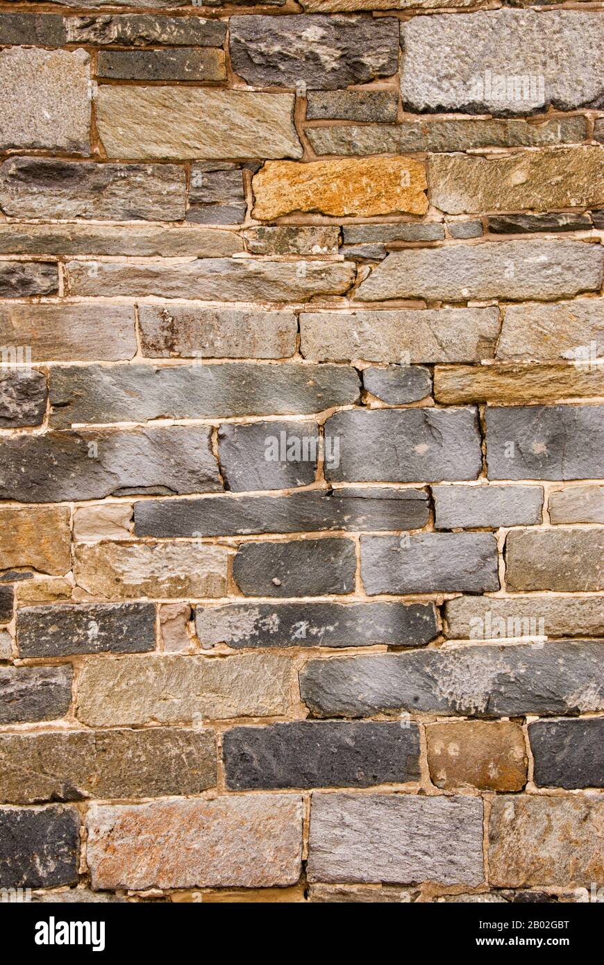 Les roches et les pierres grises et brunes de cet ancien mur sont tordues et inclinées dans toutes les directions. Il est plein de texture et d'intérêt visuel. Banque D'Images