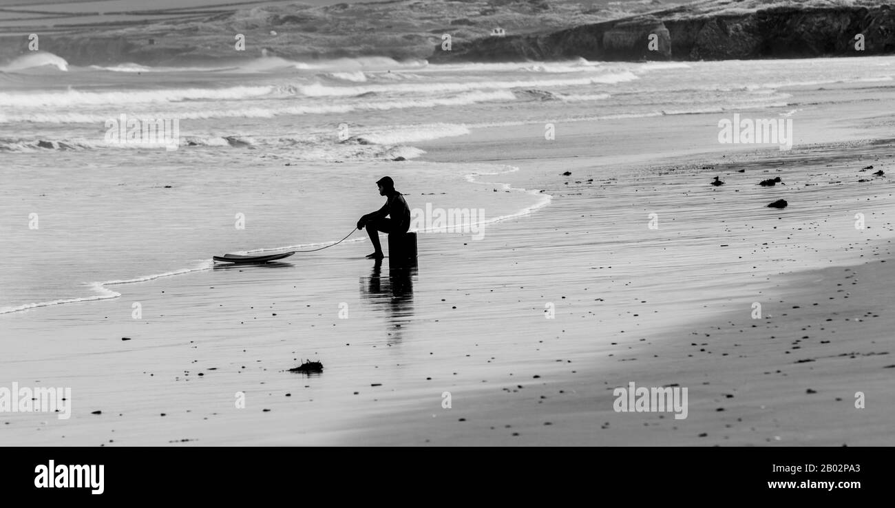 Un surfeur déjecté ou fatigué est assis sur une boîte avec son surf, Portreath, Cornwall, Angleterre Banque D'Images