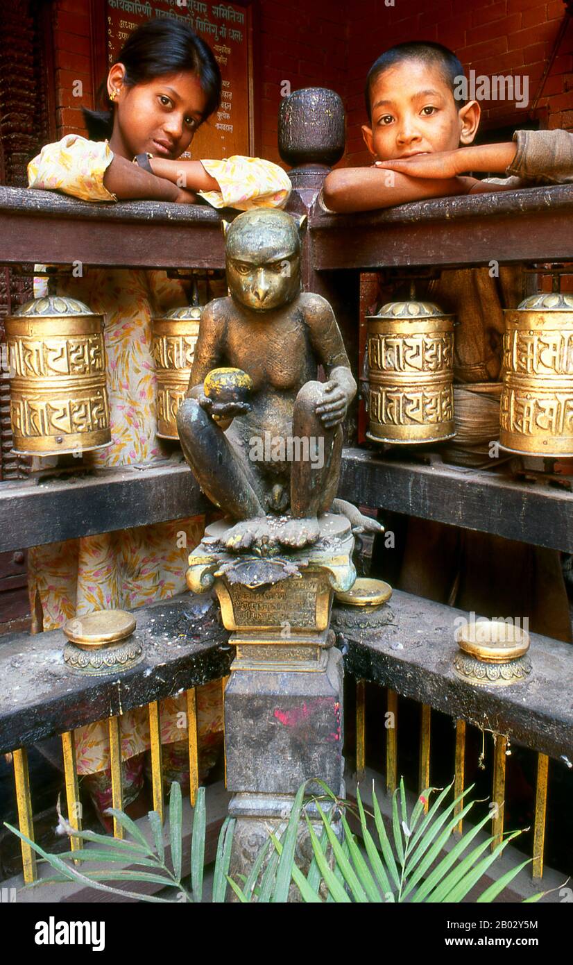 Népal: Une statue de bronze du dieu hindou Hanuman se trouve dans un coin au milieu des roues de prière bouddhiste à l'intérieur du Temple d'Or (Hiranyavarna Mahavihara), Patan, Vallée de Katmandou (1998). Le Hiranyavarna Mahavihara, ou Temple d'Or, est l'un des plus grands spectacles d'art et d'architecture de la vallée de Katmandou. Soi-disant fondé au 12th siècle par le roi Bhaskara Deva Varma, le temple, tel qu'il se présente aujourd'hui, remonte pour la plupart au 18th siècle. Toute la façade du sanctuaire principal est recouverte de cuivre doré, tout comme la torana très détaillée et tous les toits. Banque D'Images
