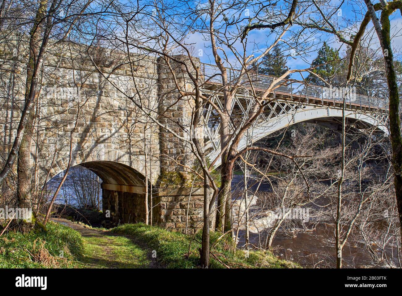 VILLAGE DE CARRON MORAY LES ARBRES DE L'ECOSSE SUR LA RIVE DE LA RIVIÈRE ENTOURENT LA ROUTE UNIQUE DE CARRON ET LE VIEUX PONT FERROVIAIRE QUI TRAVERSE LA RIVIÈRE SPEY Banque D'Images