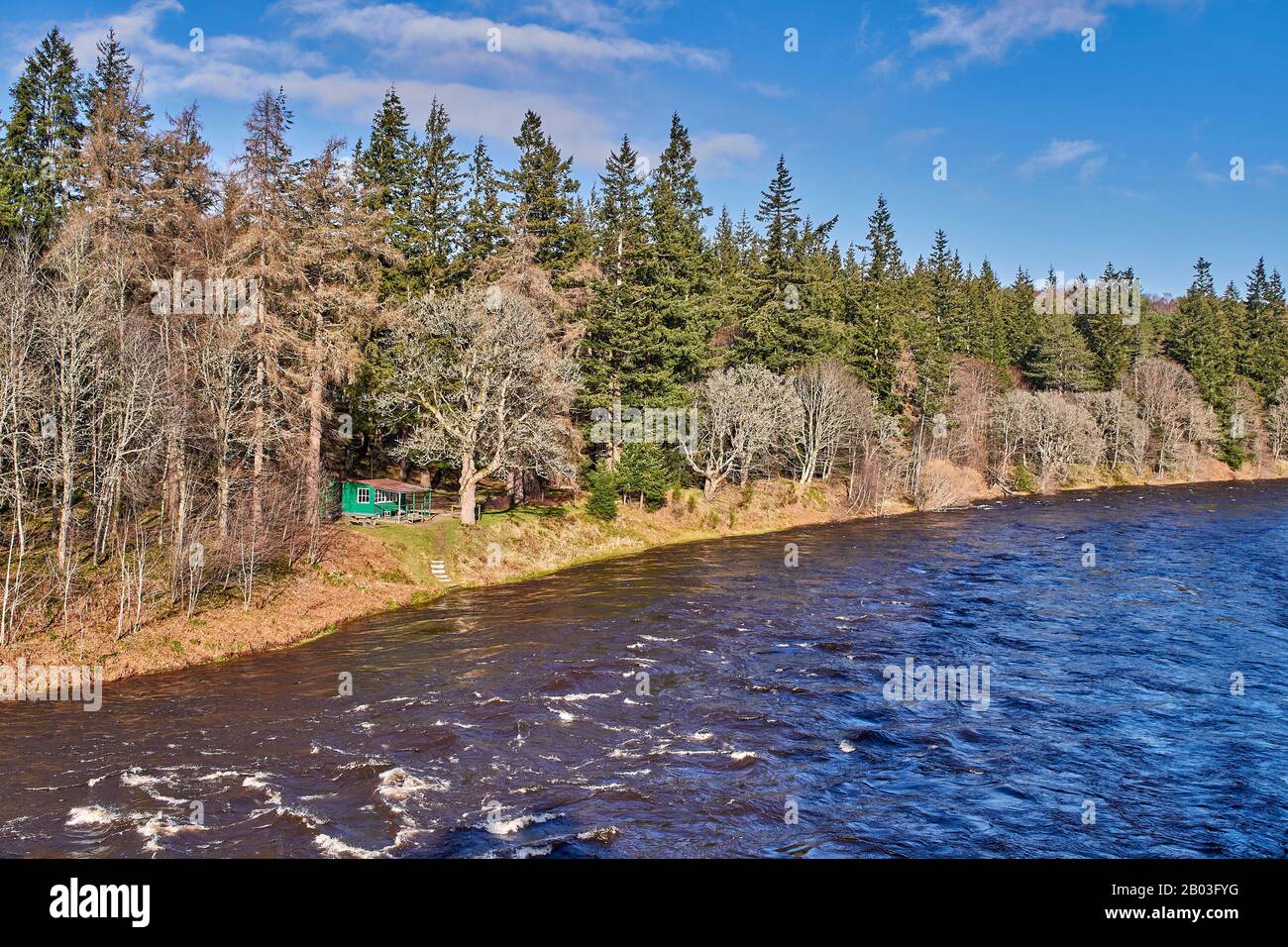VILLAGE DE CARRON MORAY ECOSSE VUE SUR UNE CABANE DE PÊCHE VERTE ET LA RIVIÈRE DEPUIS LA ROUTE UNIQUE DE CARRON ET LE VIEUX PONT FERROVIAIRE QUI TRAVERSE LA RIVIÈRE SPEY Banque D'Images
