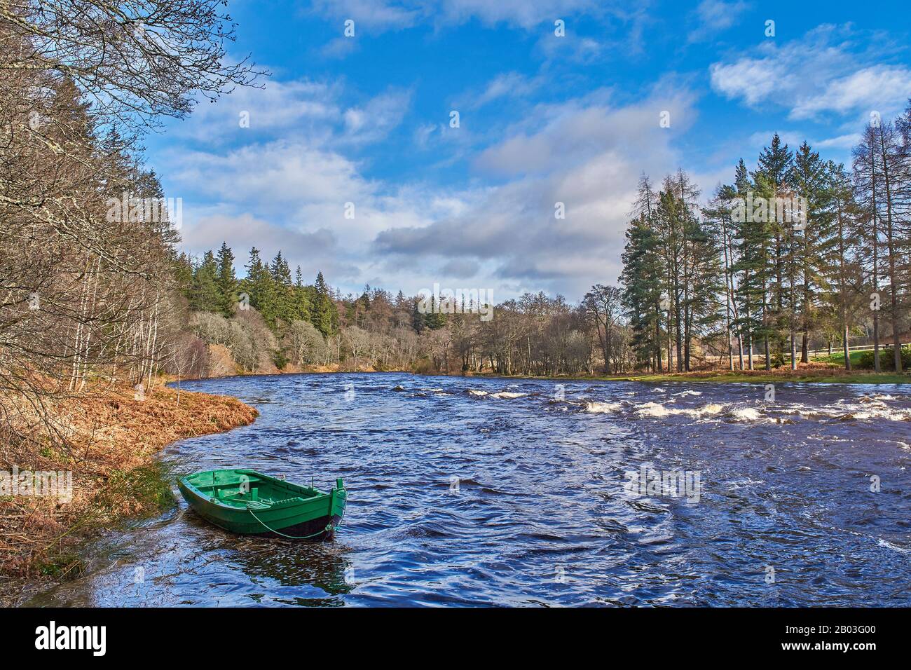 VILLAGE DE CARRON MORAY ECOSSE VUE SUR LE BATEAU DE PÊCHE VERT ET LA RIVIÈRE DEPUIS LA ROUTE UNIQUE DE CARRON ET LE VIEUX PONT FERROVIAIRE QUI TRAVERSE LA RIVIÈRE SPEY Banque D'Images