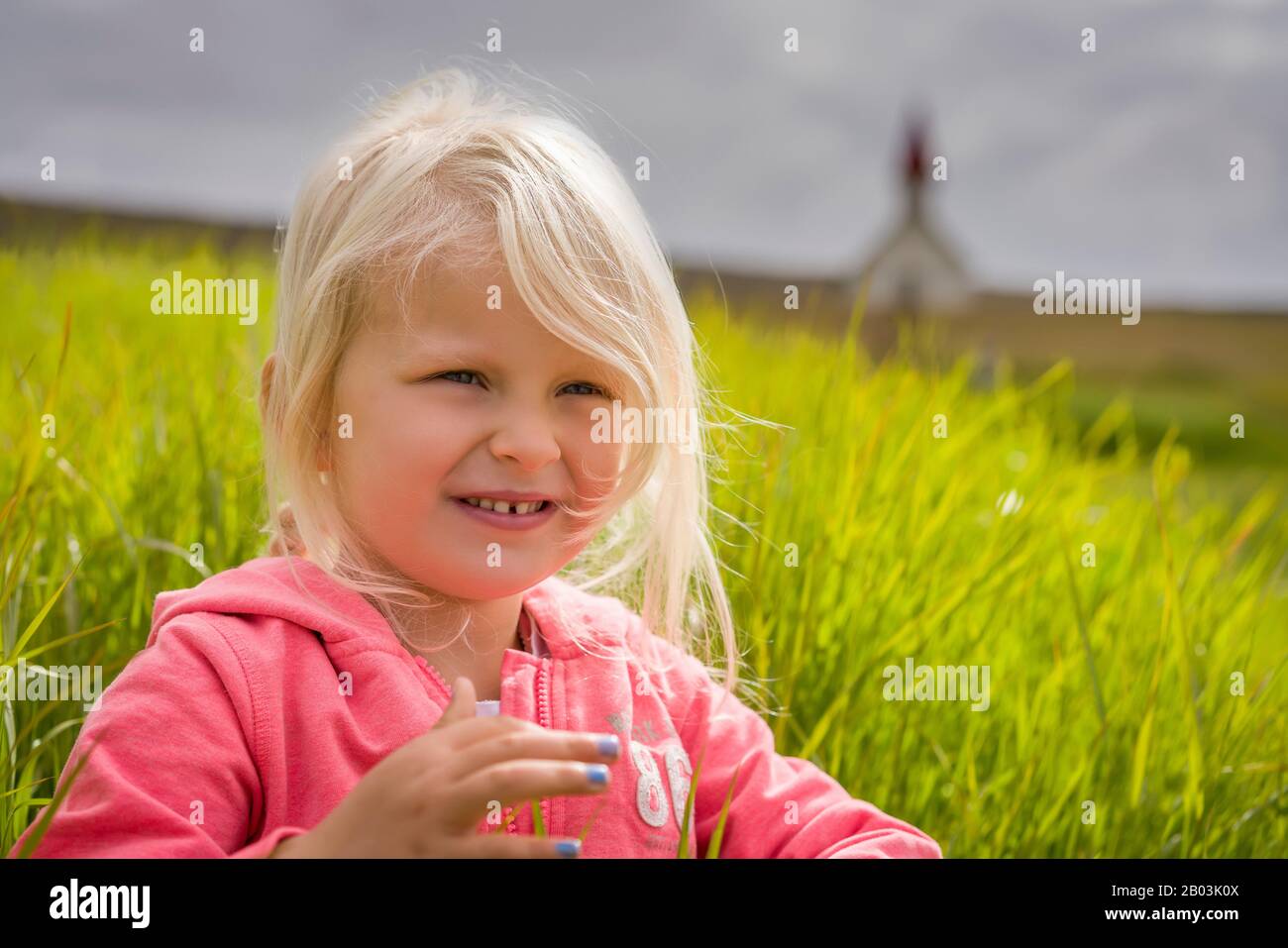 Jeune fille assise dans l'herbe, l'été, Islande Banque D'Images