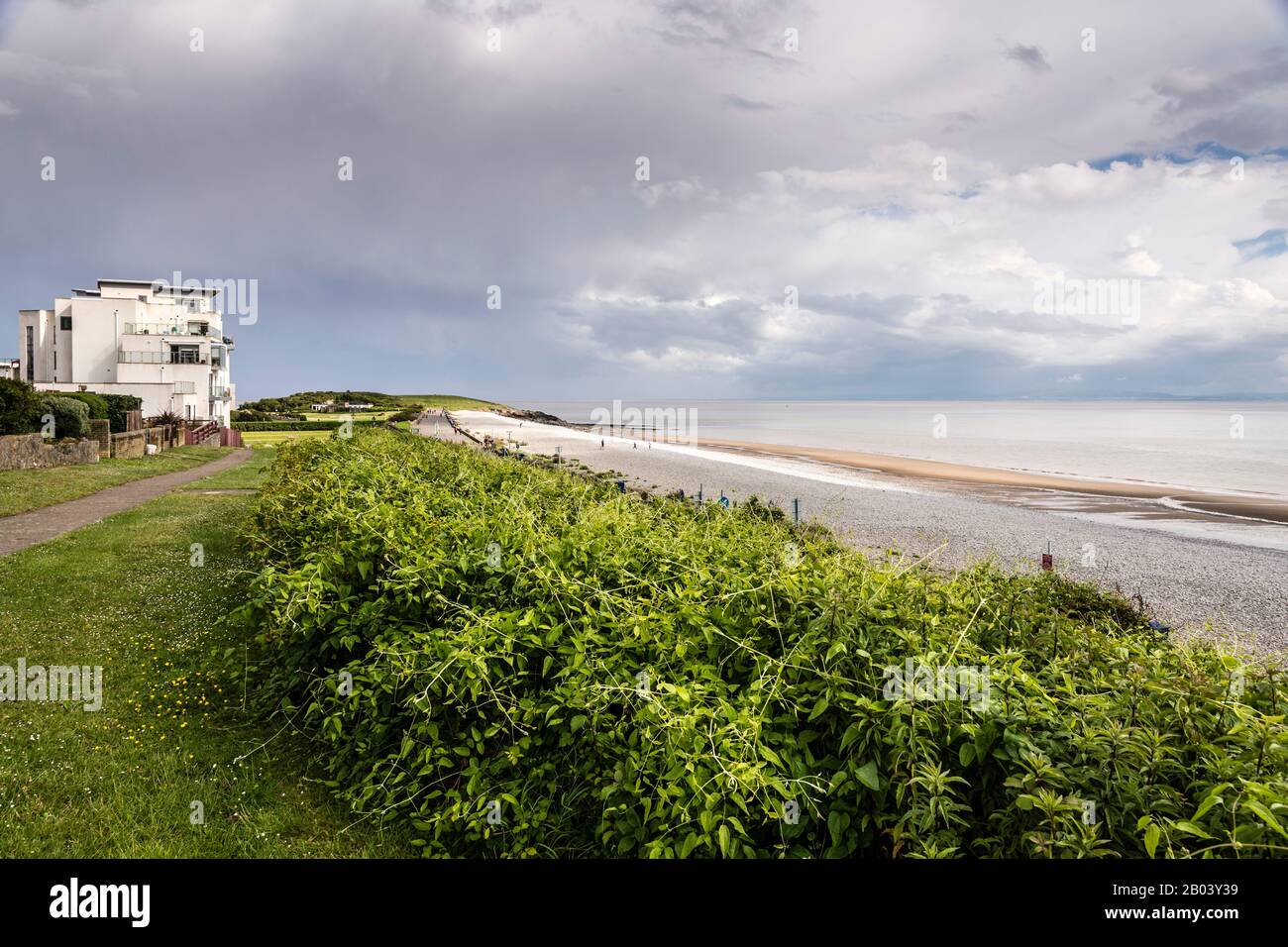 La longue plage pierreuse de la Knap, Barry, avec du sable exposé par le rivage en raison de la marée basse. La scène est calme, le soleil brille entre nuage brisé. Banque D'Images