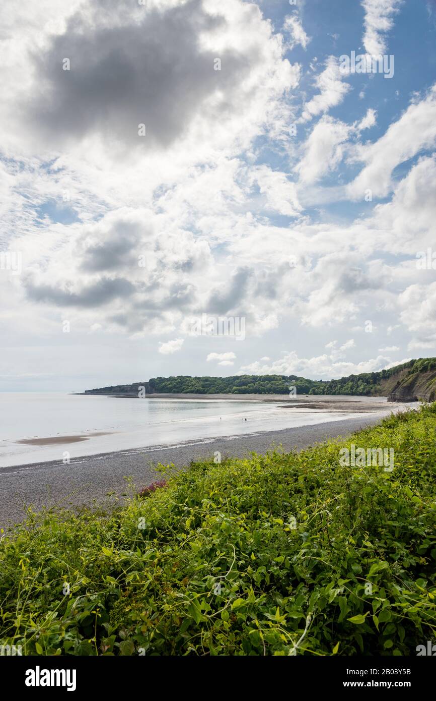 La longue plage pierreuse de la Knap, Barry, avec du sable exposé par le rivage en raison de la marée basse. La scène est calme, le soleil brille entre nuage brisé. Banque D'Images