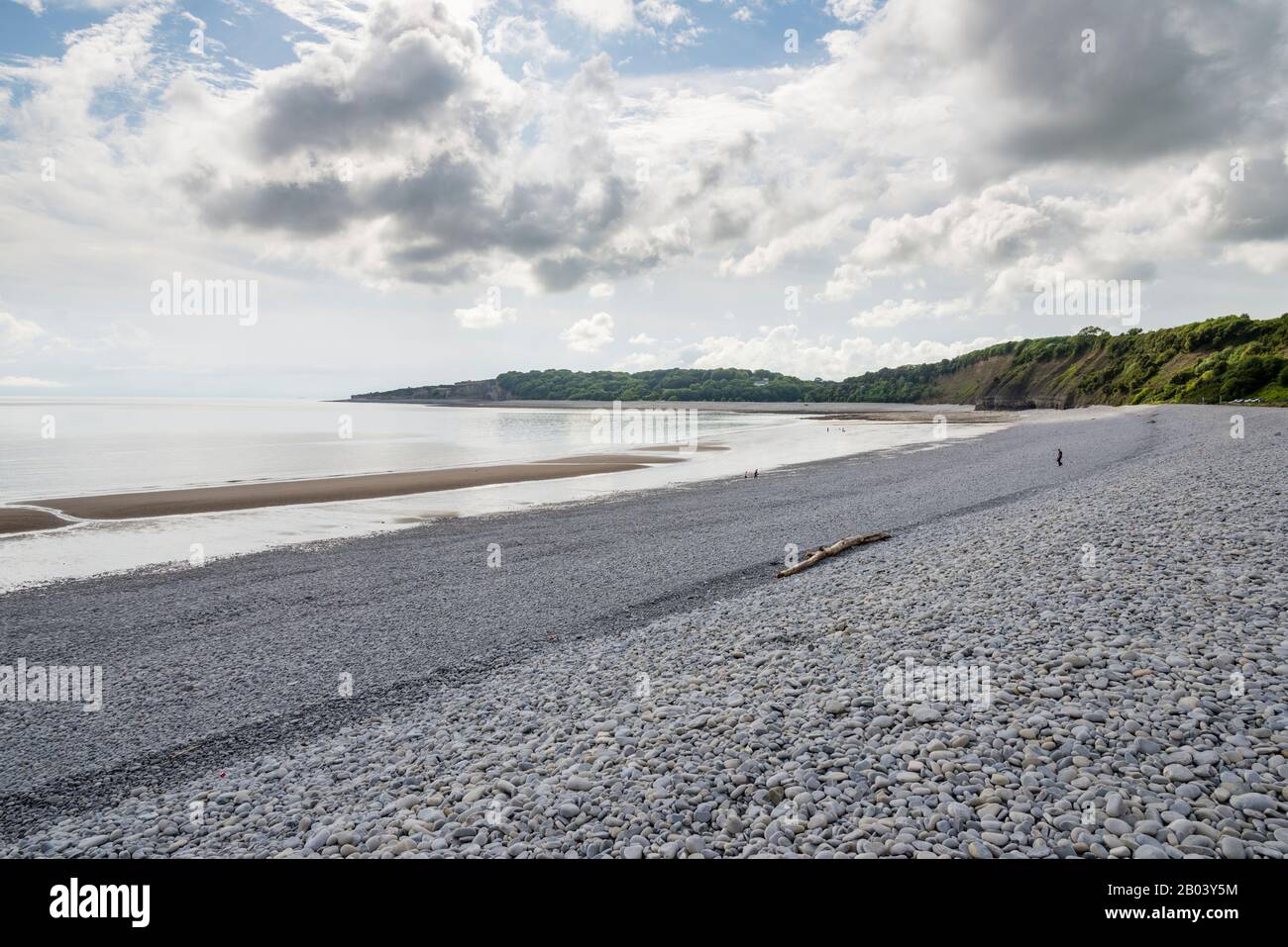La longue plage pierreuse de la Knap, Barry, avec du sable exposé par le rivage en raison de la marée basse. La scène est calme, le soleil brille entre nuage brisé. Banque D'Images