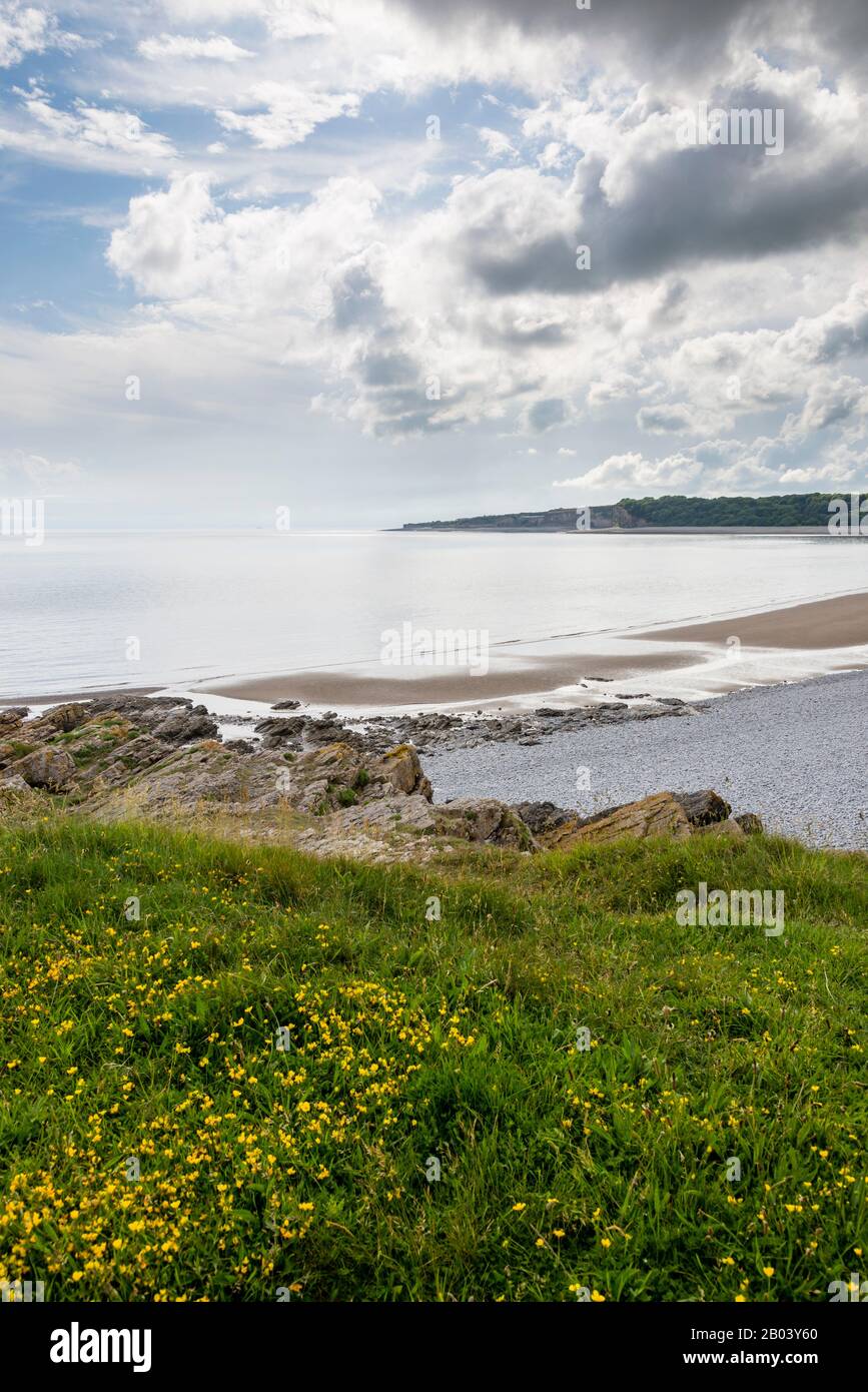La longue plage pierreuse de la Knap, Barry, avec du sable exposé par le rivage en raison de la marée basse. La scène est calme, le soleil brille entre nuage brisé. Banque D'Images