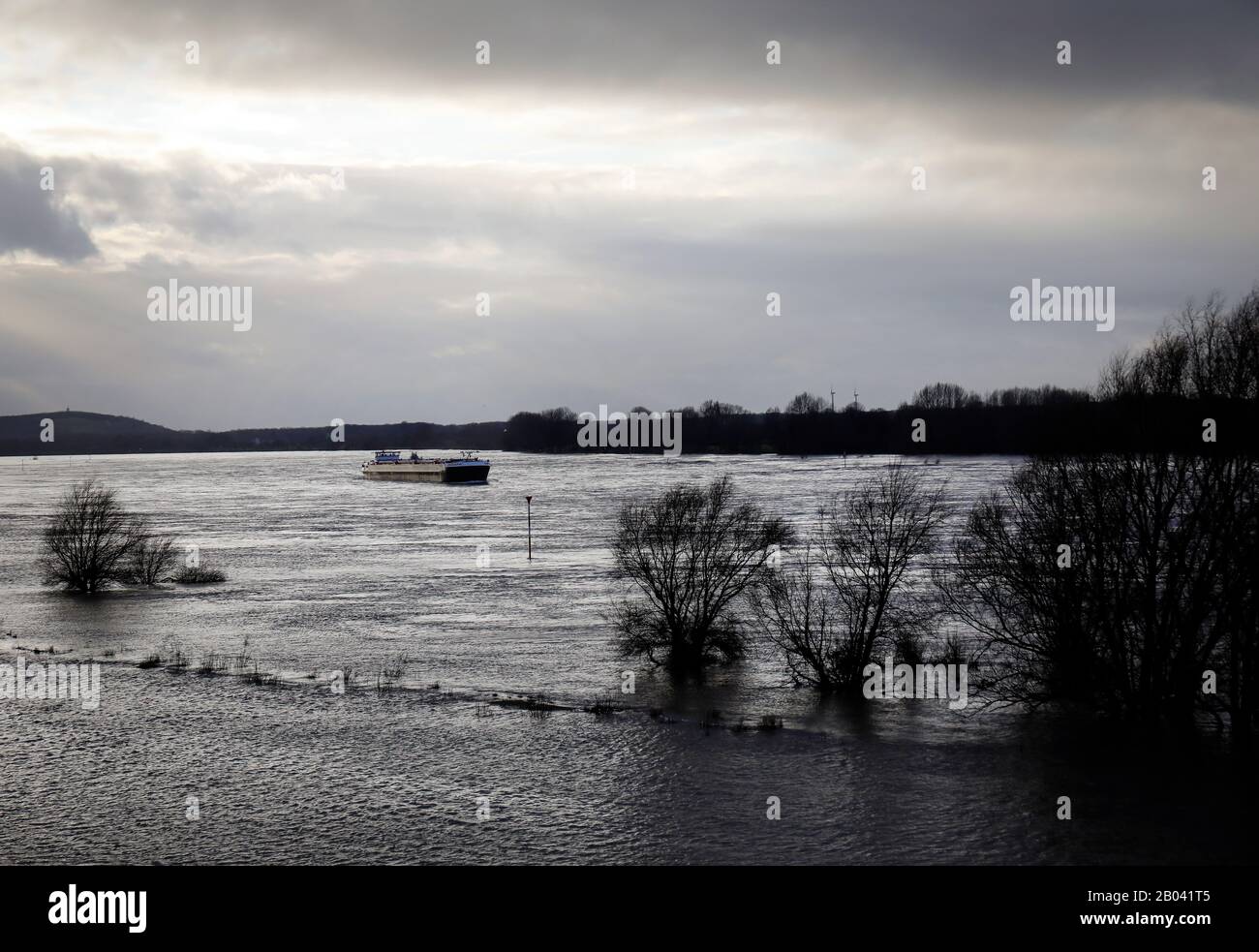 Duisburg, région de la Ruhr, Rhénanie-du-Nord-Westphalie, Allemagne - un cargo navigue sur le Rhin à Duisburg-Marxloh en haute eau dans un ciel pluvieux sombre. Duisb Banque D'Images