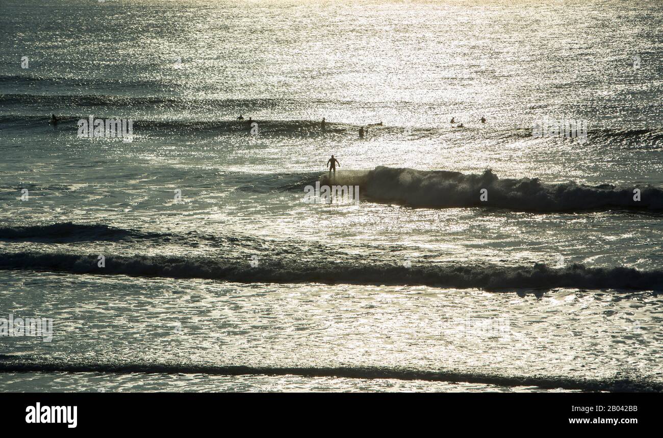 Un surfeur fait une vague tandis que d'autres surfeurs attendent, Fistral Beach, Newquay, La Cornouaille Coast, Angleterre Banque D'Images