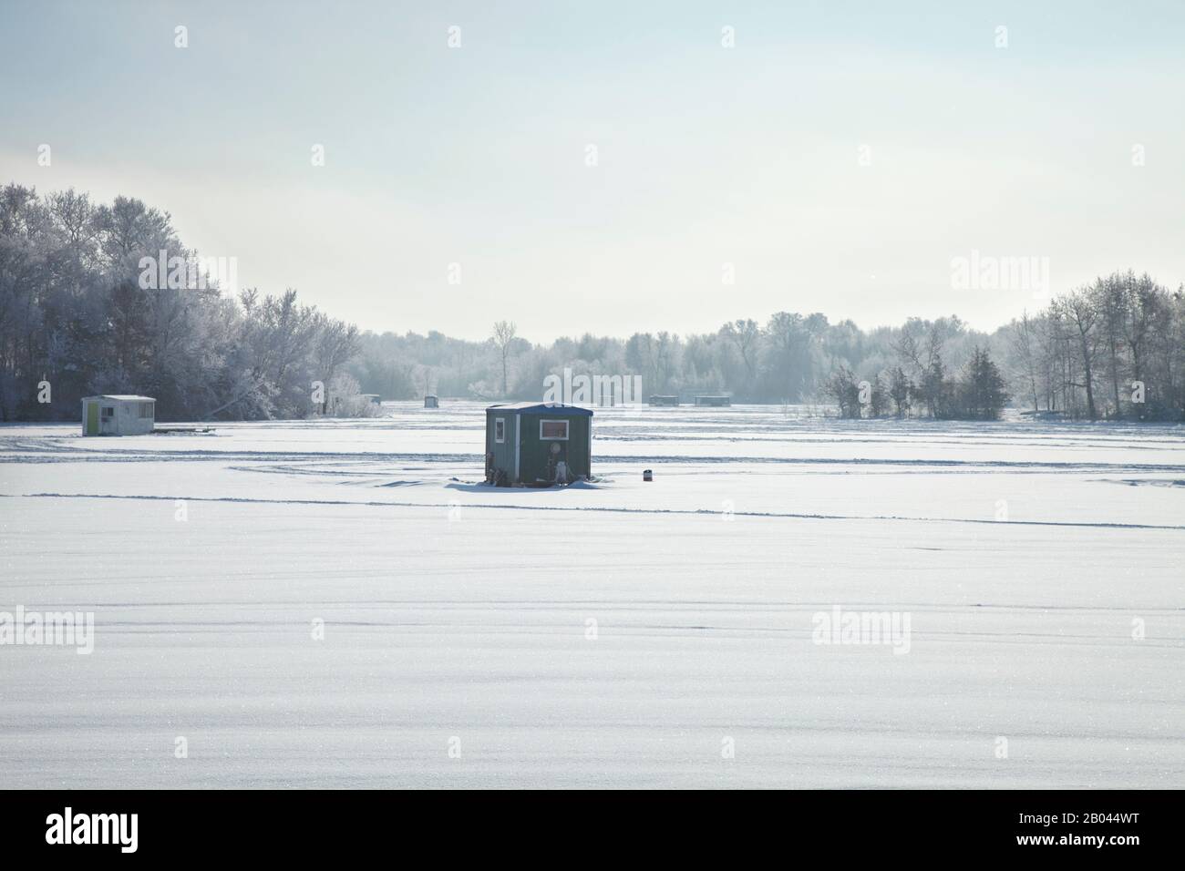 Des cabanes de pêche sur glace et des remorques dans un lac du Minnesota, un matin d'hiver brillant Banque D'Images