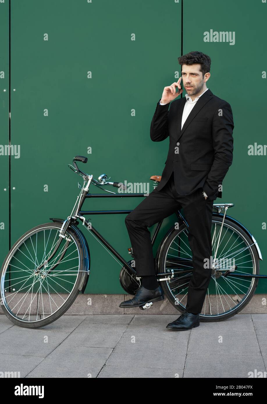 l'homme vêtu d'un costume avec un vélo classique parle au téléphone Banque D'Images
