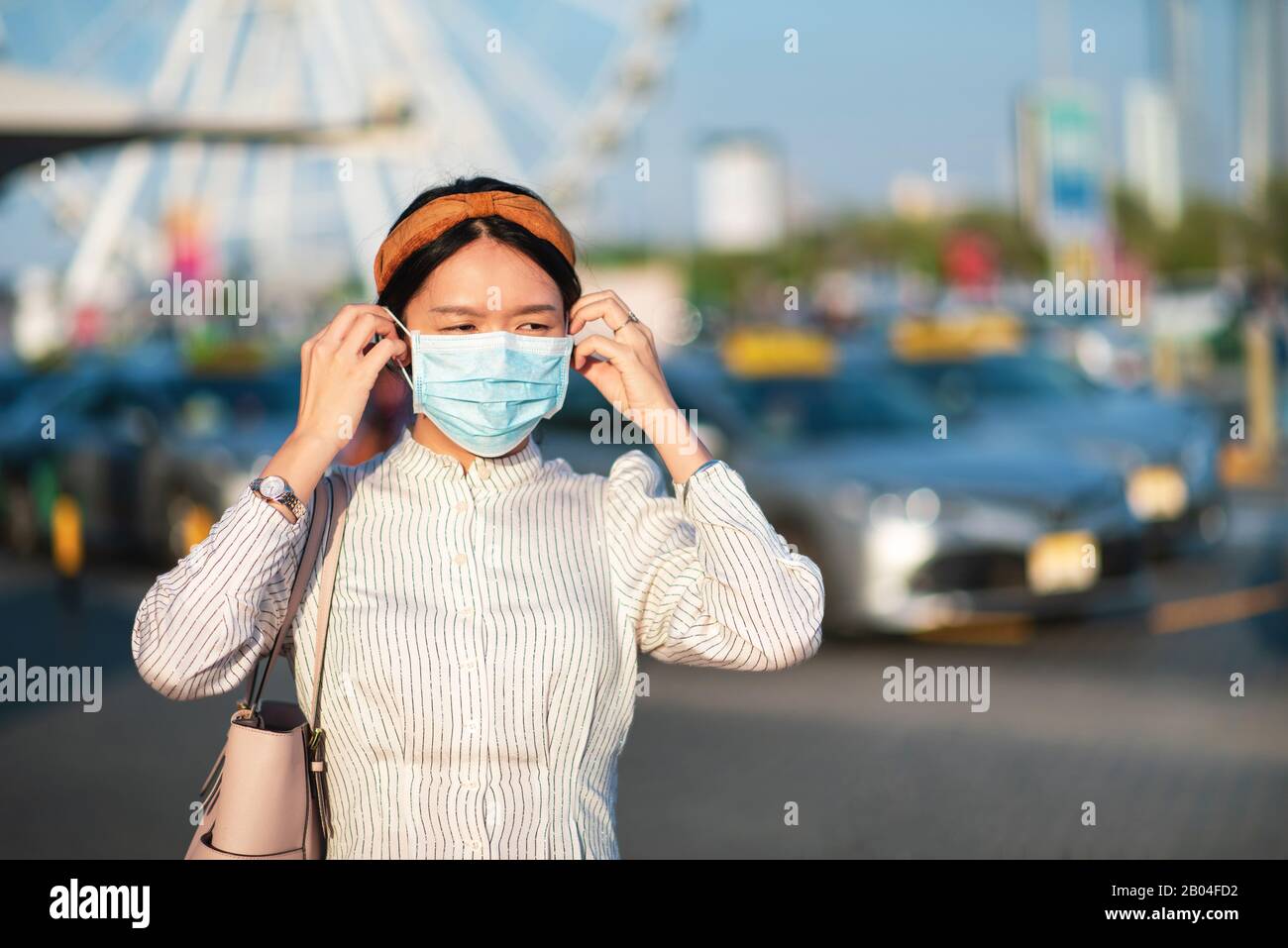 Fille asiatique portant un masque de visage sur un parking extérieur Banque D'Images