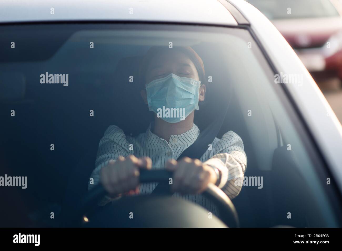 Fille asiatique portant un masque de visage dans une voiture à l'extérieur Banque D'Images