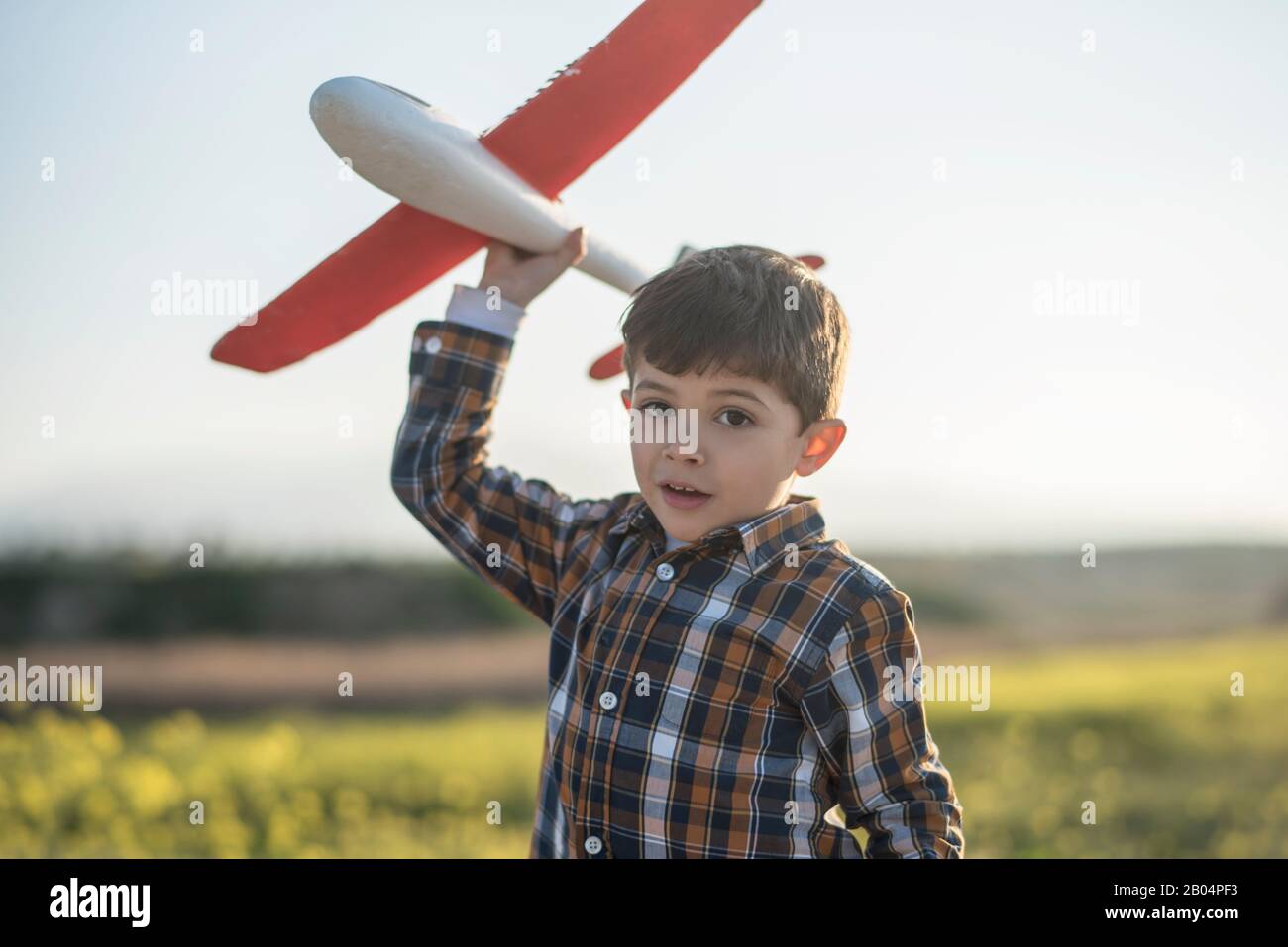 Petit garçon avec un avion jouet jouant au printemps extérieur image Banque D'Images
