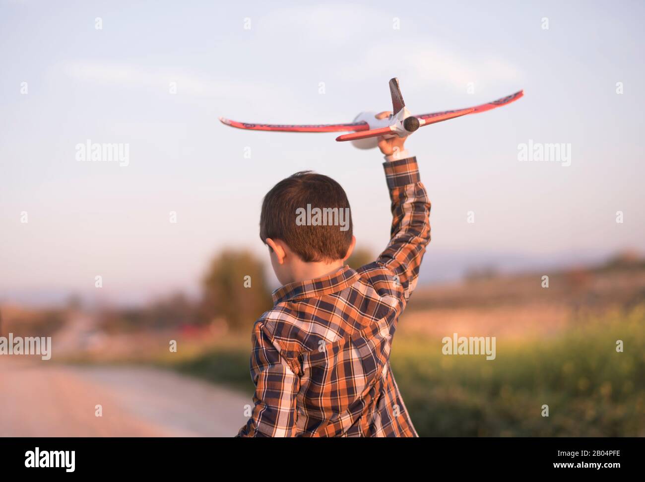 Petit garçon avec un avion jouet jouant au printemps extérieur image Banque D'Images